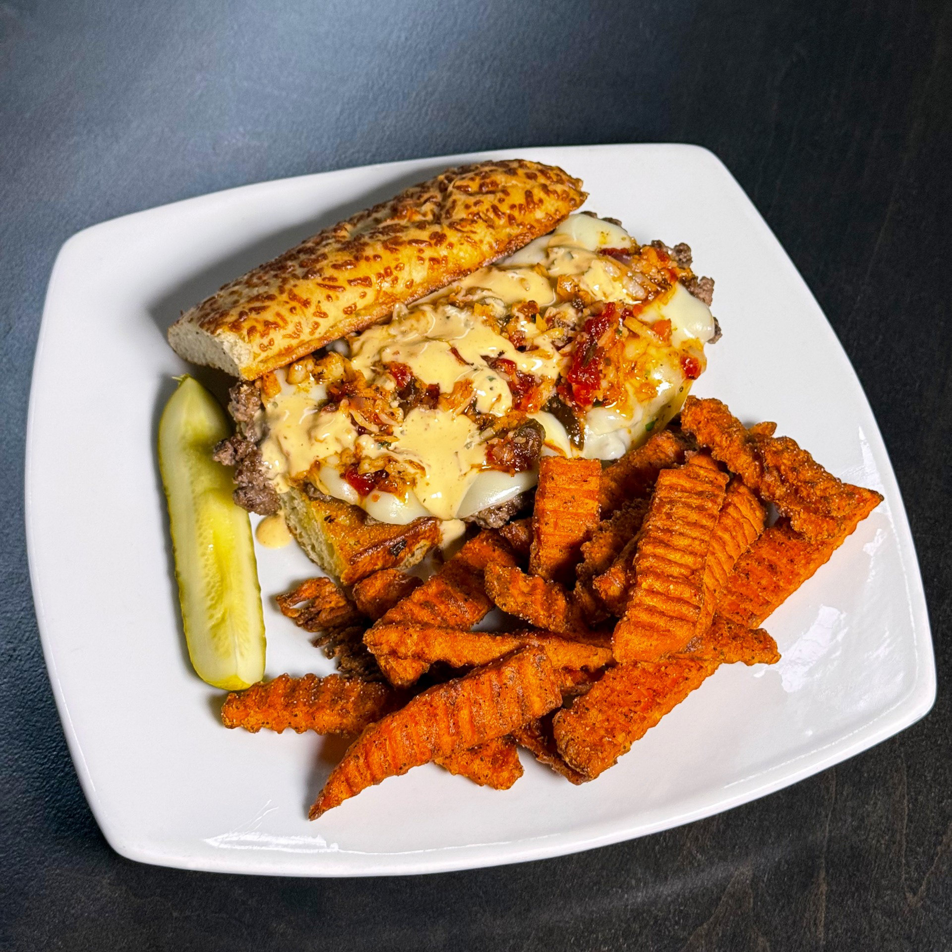 The "Lobsteer" Burger - Holiday Inn - A sizzling smash burger seasoned with our signature house spice blend, draped in silky provolone and crowned with a luscious red-pepper lobster jam. Finished with shrimp and a smoky chipotle ranch, all tucked inside a warm, parmesan-crusted baguette. Served with your choice of side.  