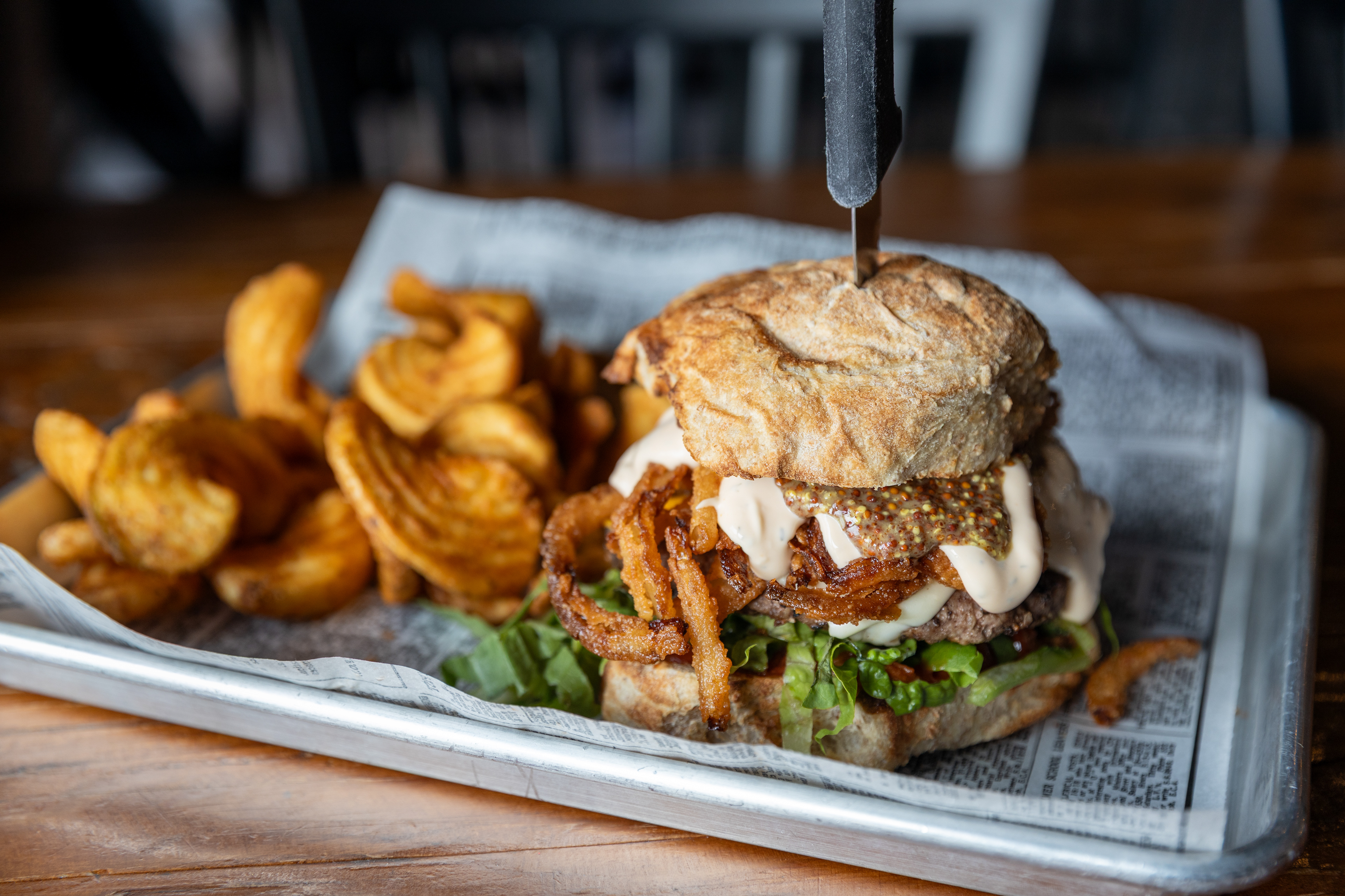 The Brewmaster Burger - Remedy Brewing Co. - The Brewmaster Burger is everything you love about a brewery. A rich, buttery Queen Bee Wheat Bun with a decadently tender local Wagyu beef patty. Sweet-savory tomato jam meets velvety cold-smoked American cheese, while crisp shrettuce and ultra-light fried onion tanglers add the perfect texture and crunch. Crowning the burger is a bright, tangy duo of dill beer cheese aioli and beer mustard that ties every note together in true brewpub fashion, served with crisp, golden Sidewinder fries. This is the burger that pairs perfectly with a pint—because it was built that way.