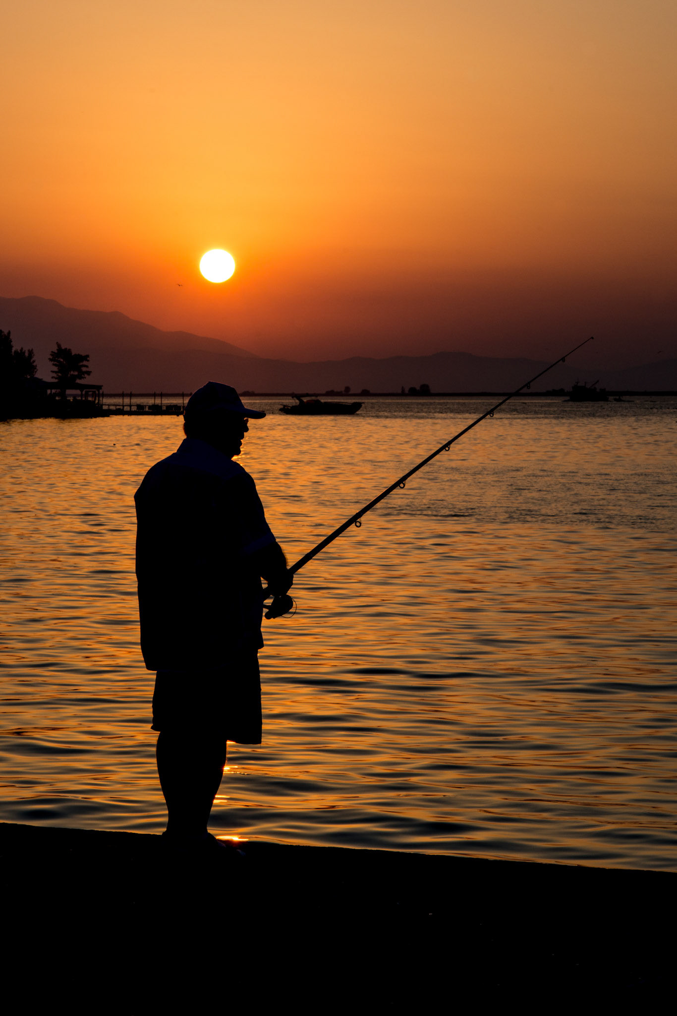 A man in fishes at sunset. Keramoti, Greece