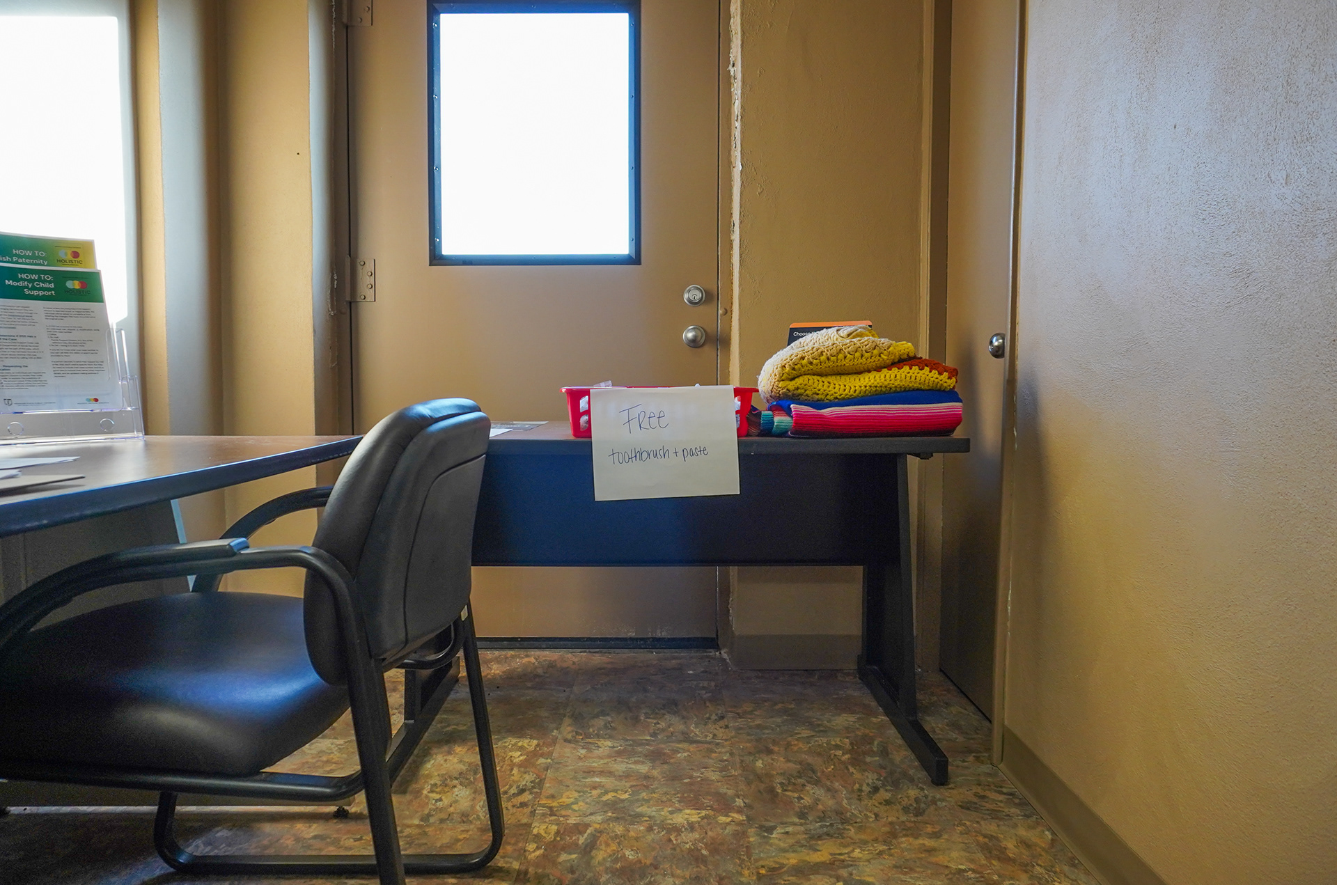 A “free toothbrush + paste” sign sits alongside free blankets in the front hallway of the Rolla office on Wednesday, Jan. 22, 2025, in Rolla, Mo. Much of the work the Holistic Defense Services do is beyond what they do for clients inside a jail or courtroom. Their philosphy of helping clients through social services includes providing a variety of goods for clients, free of charge: blankets and jackets in the winter, clothing for their kids, and NARCAN nasal spray.