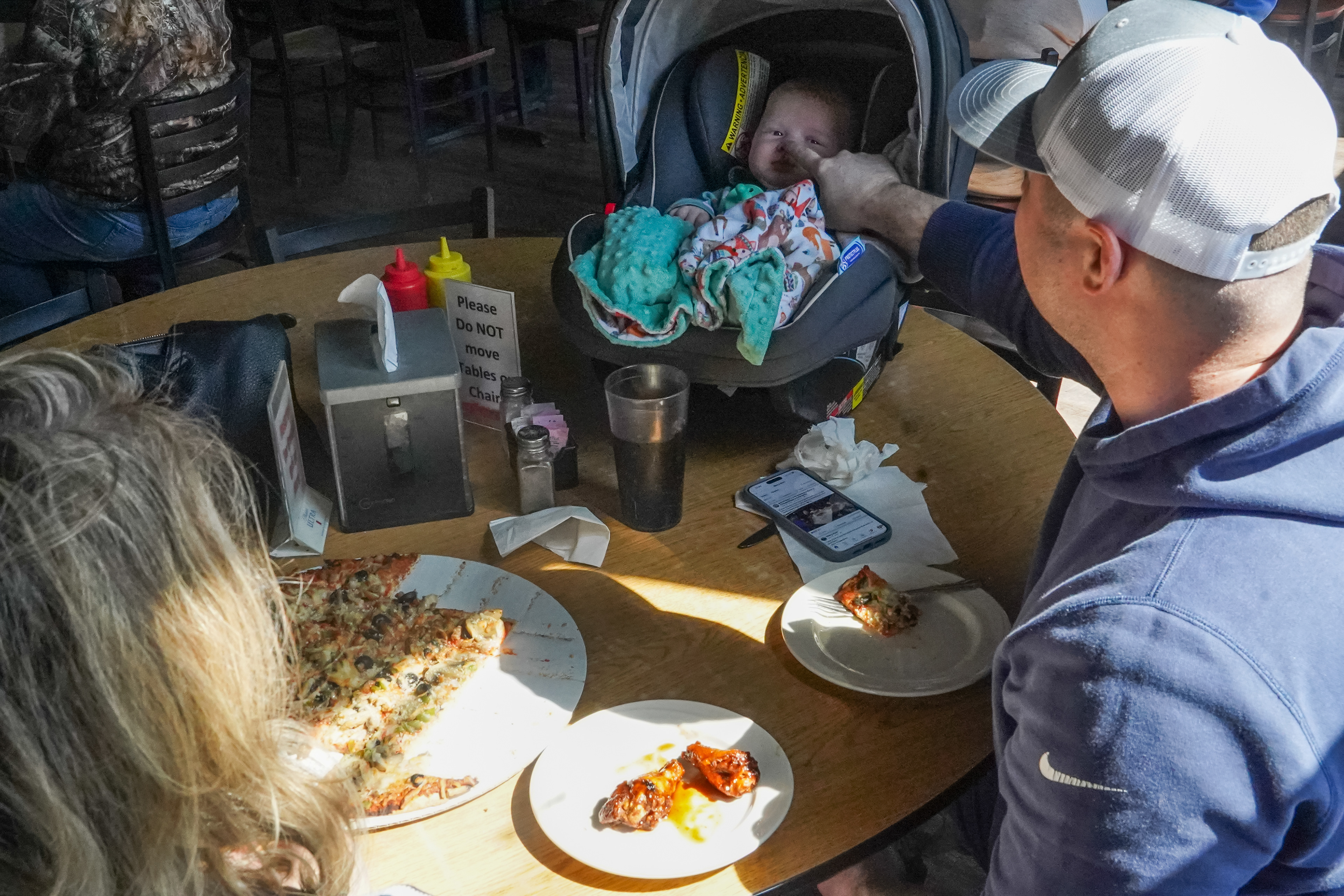 From left, Jennifer Gross eats lunch with her son Ryan Gonzalez and granddaughter Hadley Gonzalez, three months, on Tuesday, March 19, 2024, at the Sharp Corner Tavern in Hermann, Mo. “My husband is from Hermann. Everybody knows everybody. Even if you don’t know the full name, you know so and so. They’re all somehow connected.” Gross said as she pointed across the bar to the Murphys, fellow tavern regulars.