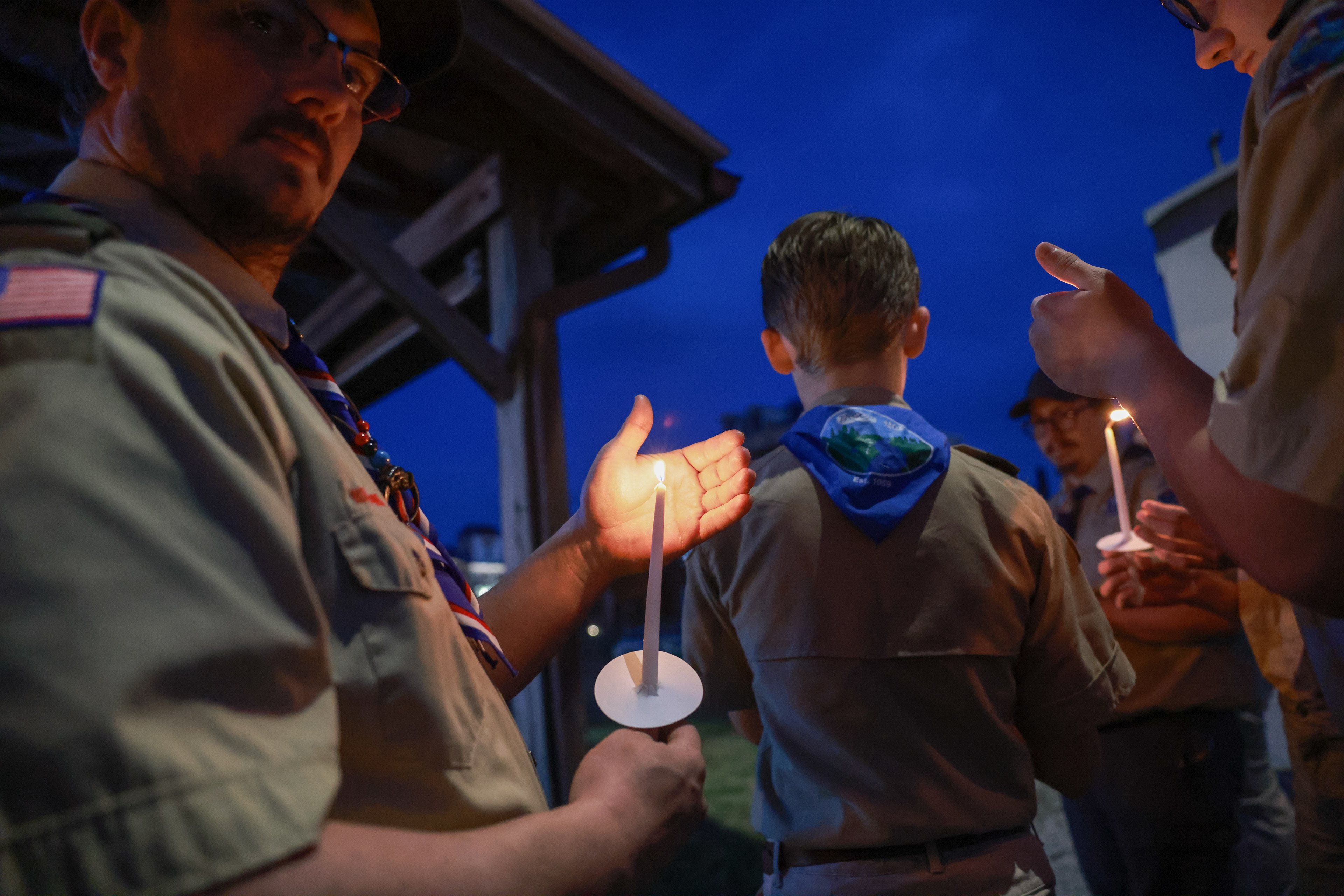 Boy Scouts 116 assistant troop master John Steiner III holds a candle during the vigil of Hermann police Sgt. Mason Griffith on Tuesday, March 14, 2024, in Hermann, Mo. The vigil for Sgt. Griffith marked the one year memorial of his death on duty, where he passed away after a standoff with an armed gunman at a local convenience store.  