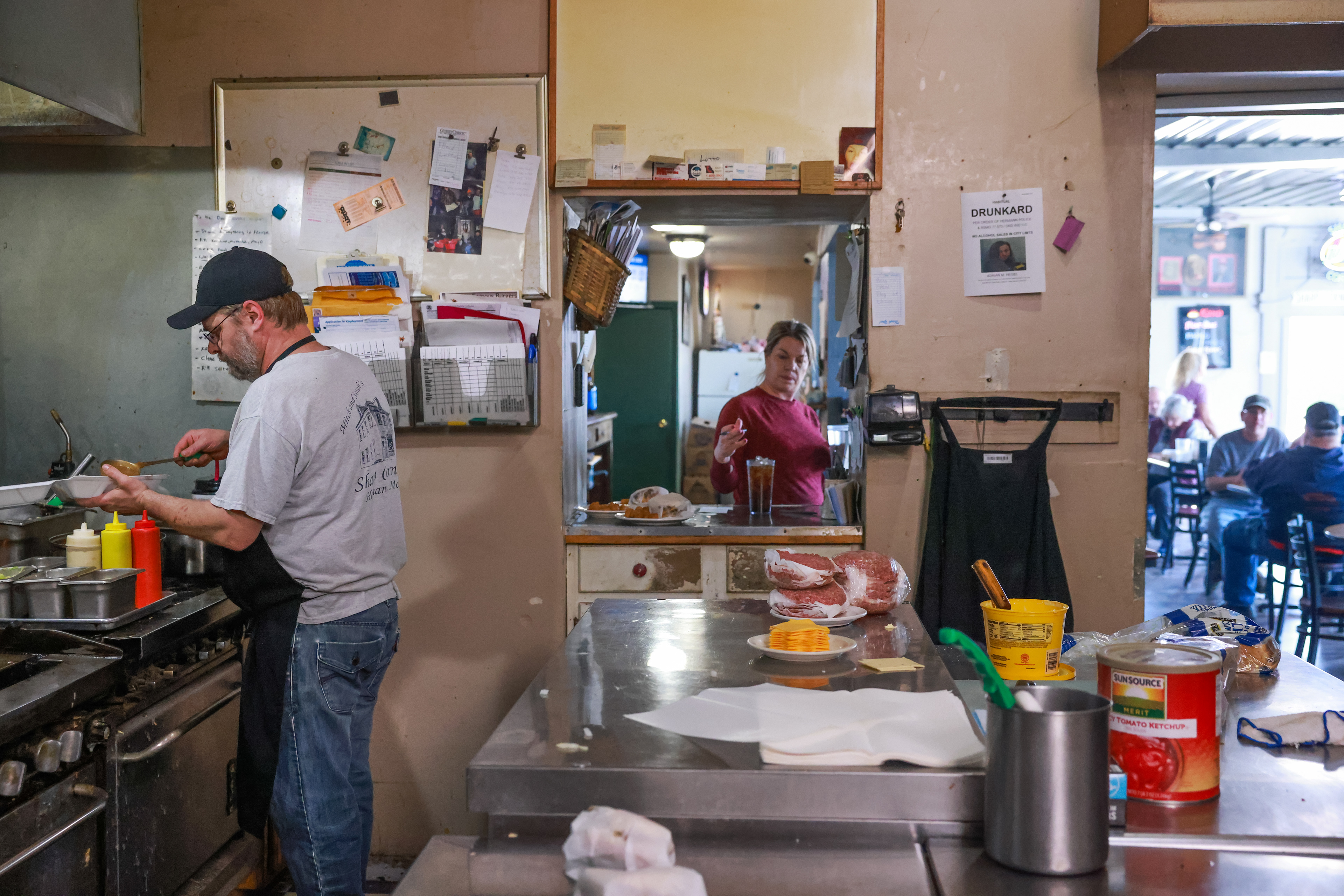 Toby Hoelmer, left, and Sarah Hoelmer run the lunch rush on Tuesday, March 12, 2024, at the Sharp Corner Tavern in Hermann, Mo. The kitchen is a square unit consisting of a cast iron griddle, decades-old burners and a deep fry station.