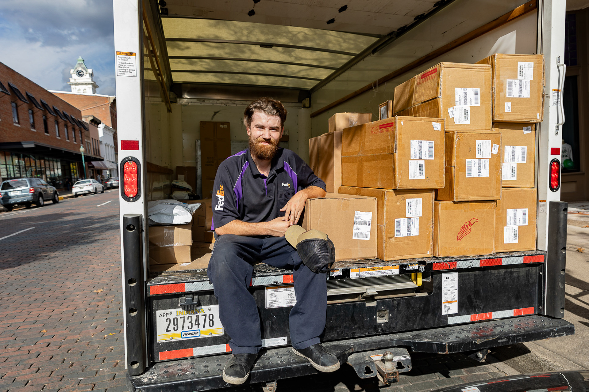 Will Wright poses for a portrait in the back of his company truck on Court Street, Athens,  Ohio, Oct. 26, 2023. Wright grew up in Albany, Ohio, and joined the army straight out of  high school. “I wanted to go into the police force after I got out of the military, but their  wage here in Athens is just not enough.” A friend recommended the FedEx job to Wright,  who then applied and was hired shortly after. “I don’t mind the job. It could be worse,  honestly."