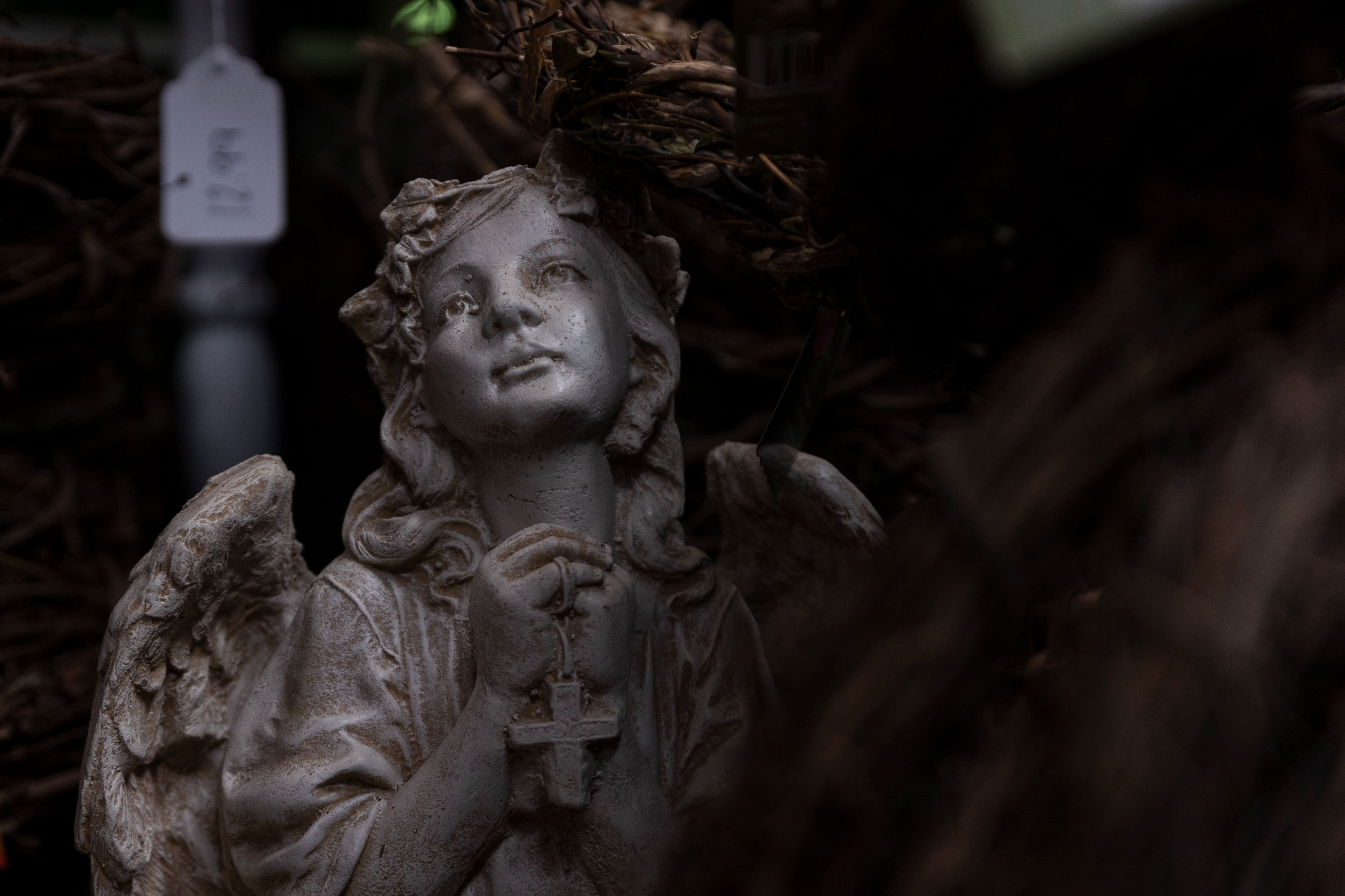 An angel statue sits on the floor amidst stacks of wreaths. "I would say 20% of business is tied to funerals and sympathy gifts," Polly said.