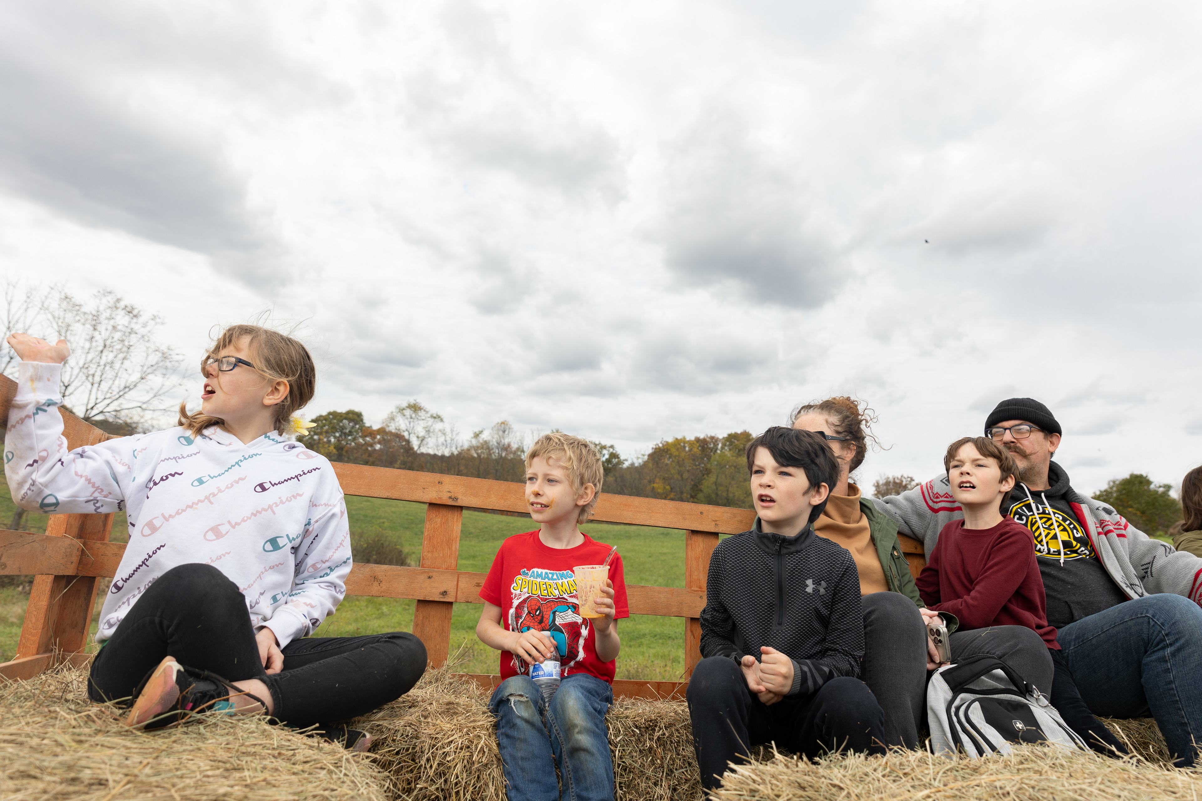 Piper (left) explains to Damien (right) what her favorite part of the hayride is while Braydin (middle) listens after finishing his pumpkin ice cream Oct. 21, 2023. For Braydin, the homemade, free pumpkin ice cream, a specialty of Libby's, is his favorite part.