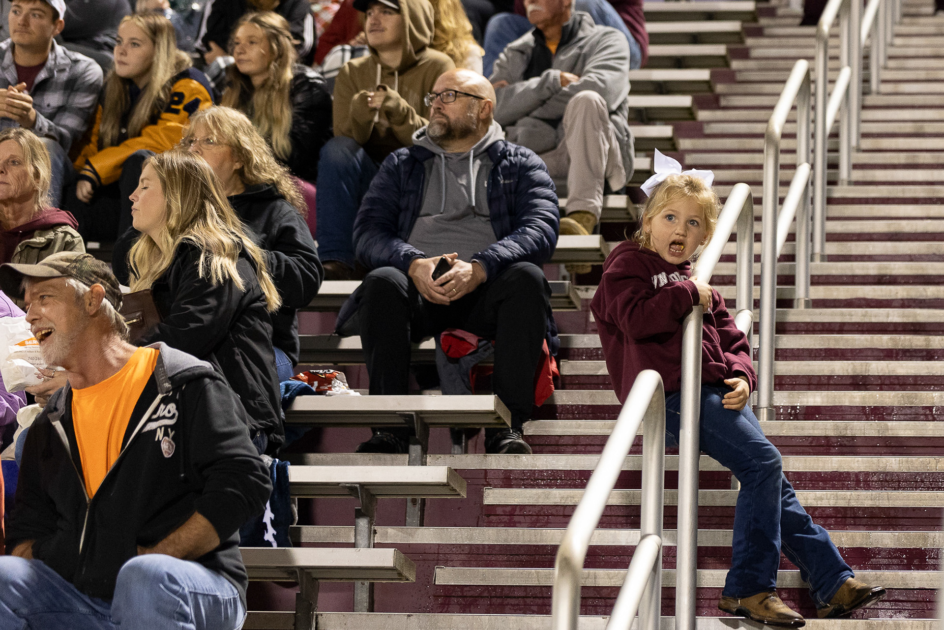 The crowd watches a Vinton County High School Vikings football game in McArthur, Ohio, Oct. 20, 2023. The stands are always sold out during home games regardless of if the weather is clear or rainy. Fans of all ages will don the Viking colors of gray and maroon to cheer on the players.