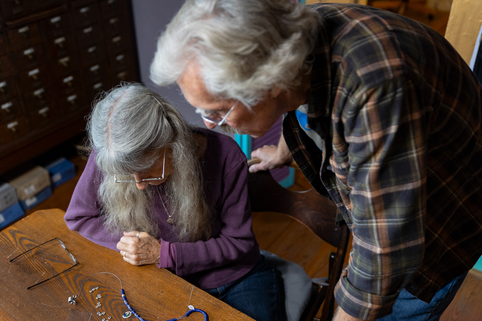 Jo Merkle and Phil Berry, owners of Beads & Things on 8 N. Shafer  St., Athens, Ohio, discuss the  pattern for a necklace Jo is working on  while the store is empty of customers on  Sept. 15, 2023. The necklace is for a  very close friend of Jo and Phil and the  two are trying to incorporate numbers  associated with religious luck into the  jewelry's pattern. "The necklace is a joint  design. He (the friend) picked the colors, and I picked the pattern. It works best  when it’s a joint project," said Jo.