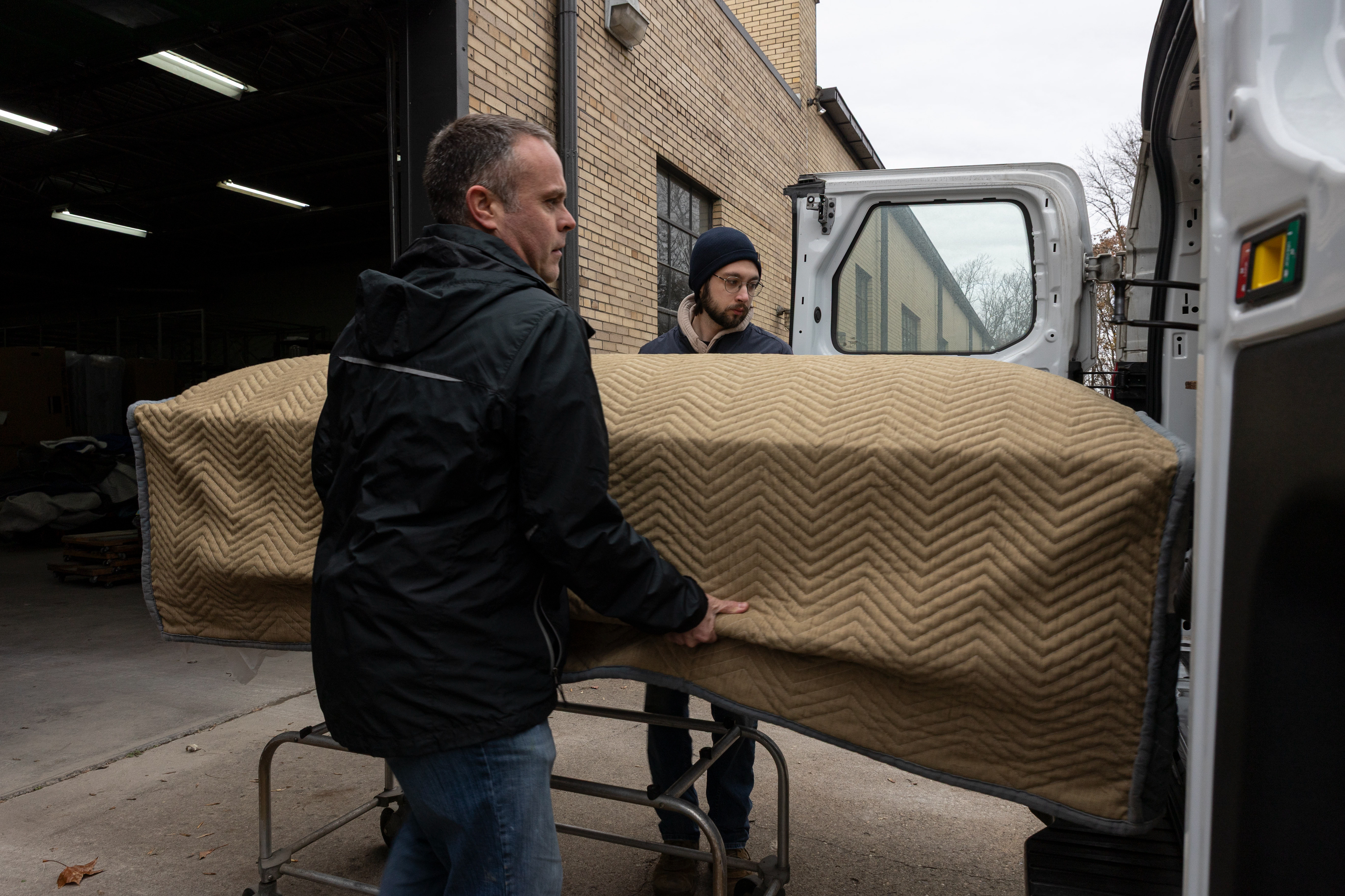 Ross Pattison and Tyler Hunley load a casket into the back of one of the company's vans. Zane Casket Company owns two vans, and Daniel drives a Chevrolet Suburban in order to deliver orders to funeral homes that can't pick up the caskets themselves. "Everyone in this business (funerals) drives a suburban because it can fit a casket in the back," Dan said.