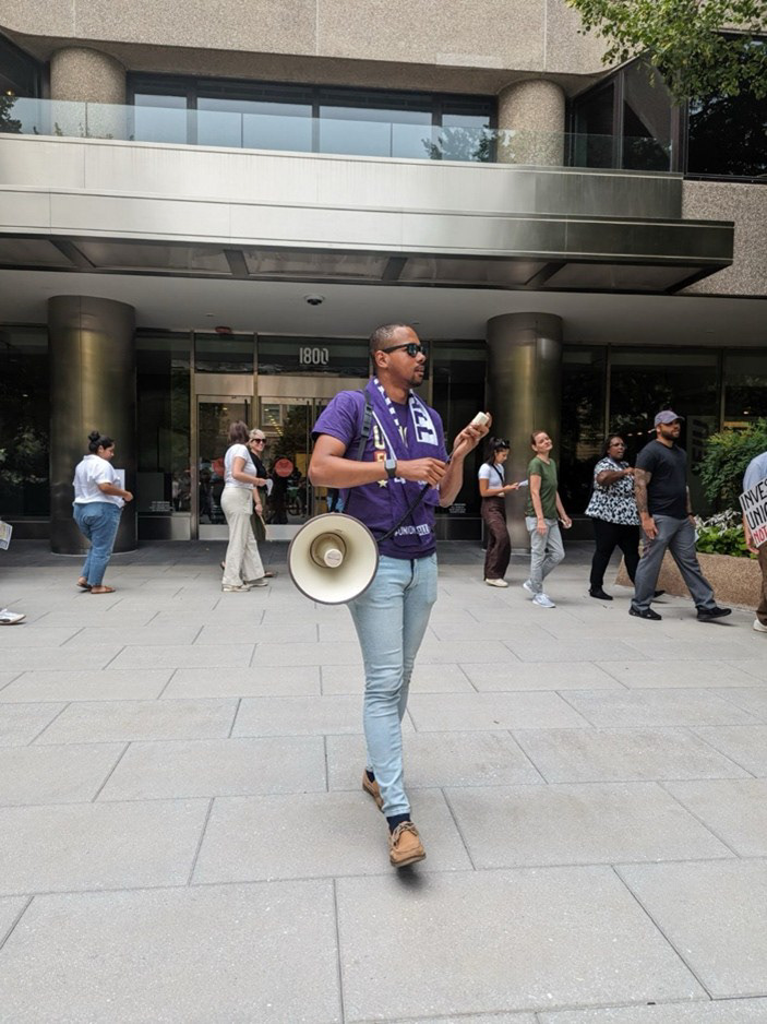 Ryan holding the megaphone to lead chants to show support to his fellow Local 2 union members in the fight for a fair contract that includes cost of living adjustments.