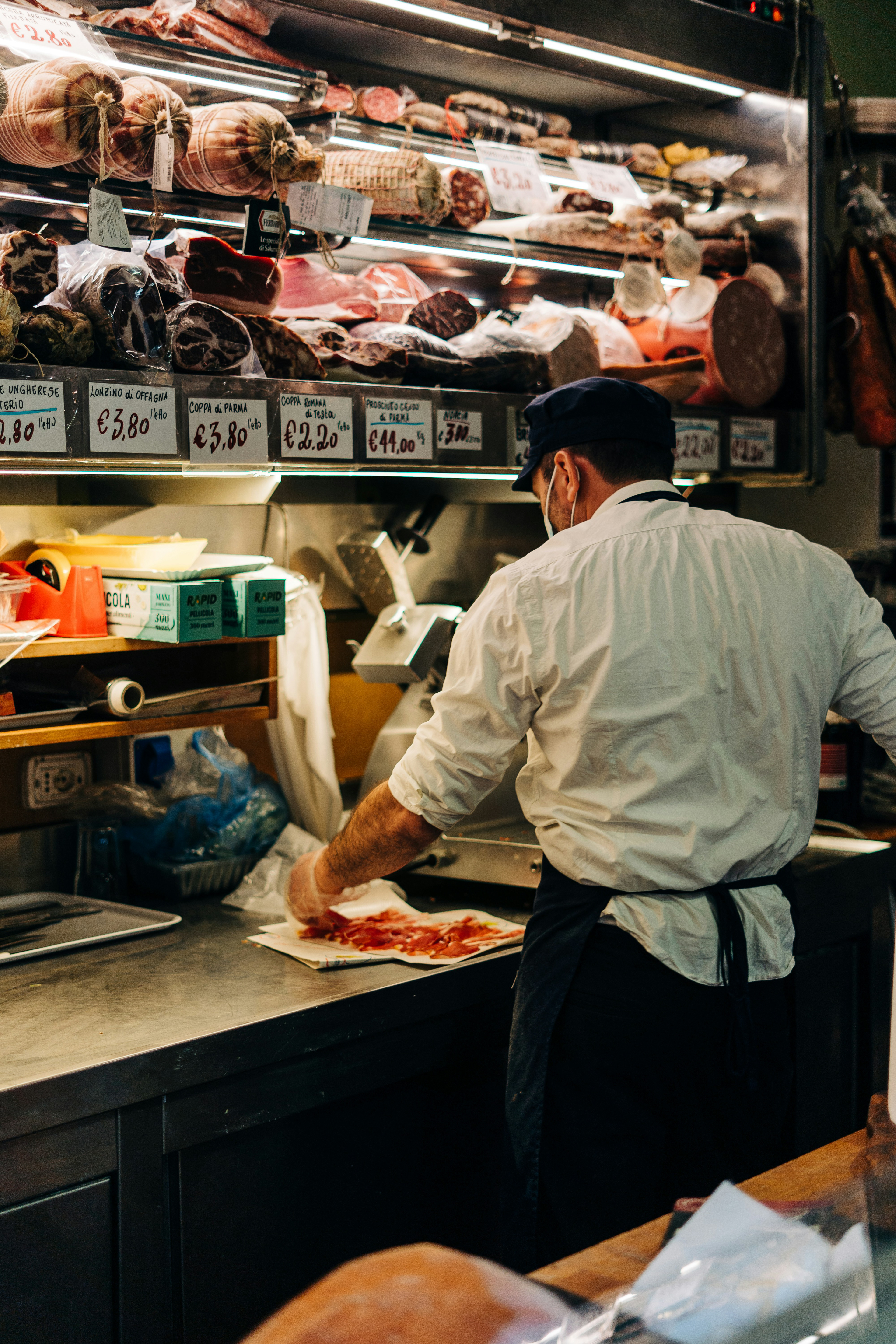 Butcher cuts slices from a ham and decorates them on a plate in a traditional butcher's shop / The Gastro Label / www.gastro-label.com