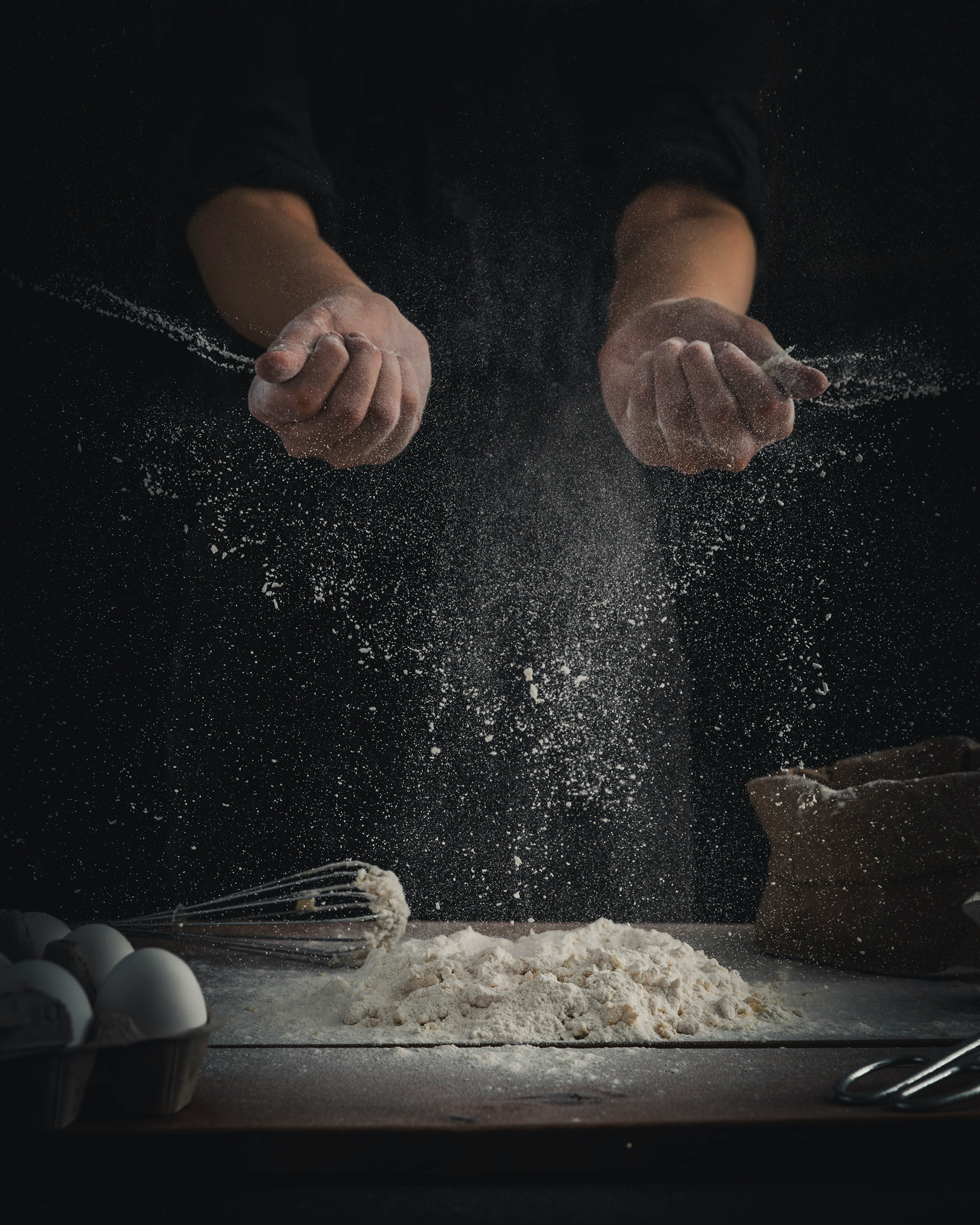 A chef scatters flour on the worktop with his hands / The Gastro Label / www.gastro-label.com
