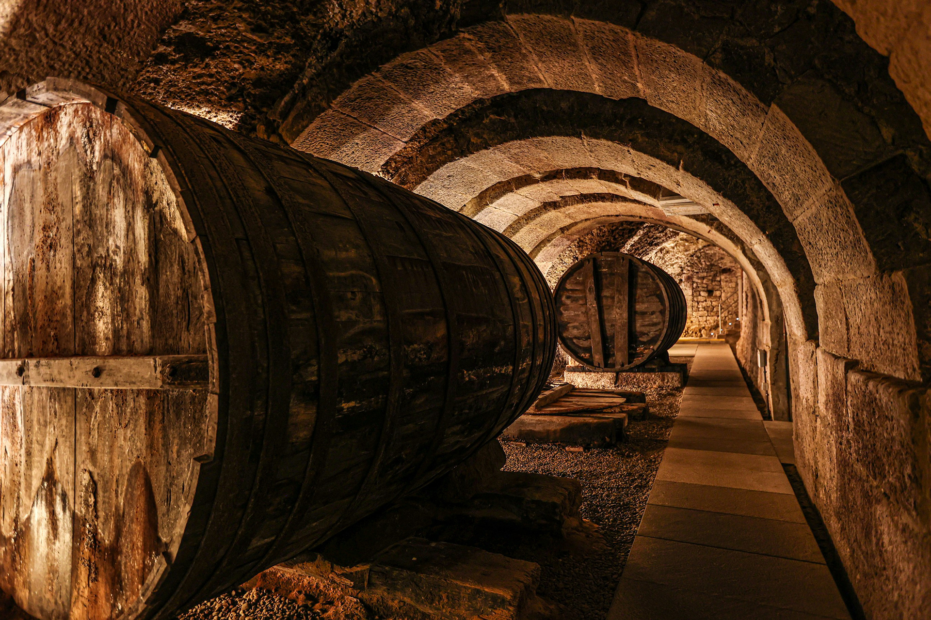 An old, very charming wine cellar with a very large wine barrel in the middle. The barrel is made from the highest quality wood / The Gastro Label / www.gastro-label.com