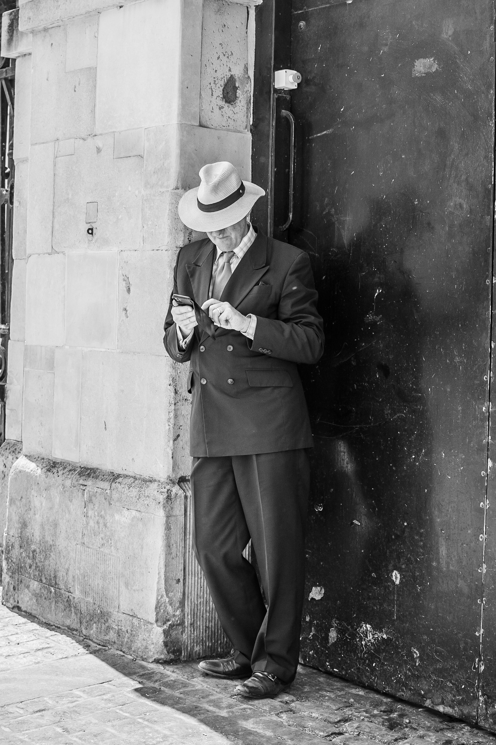 A classic mobster with a hat stands leaning against a building on a street / The Gastro Label / www.gastro-label.com