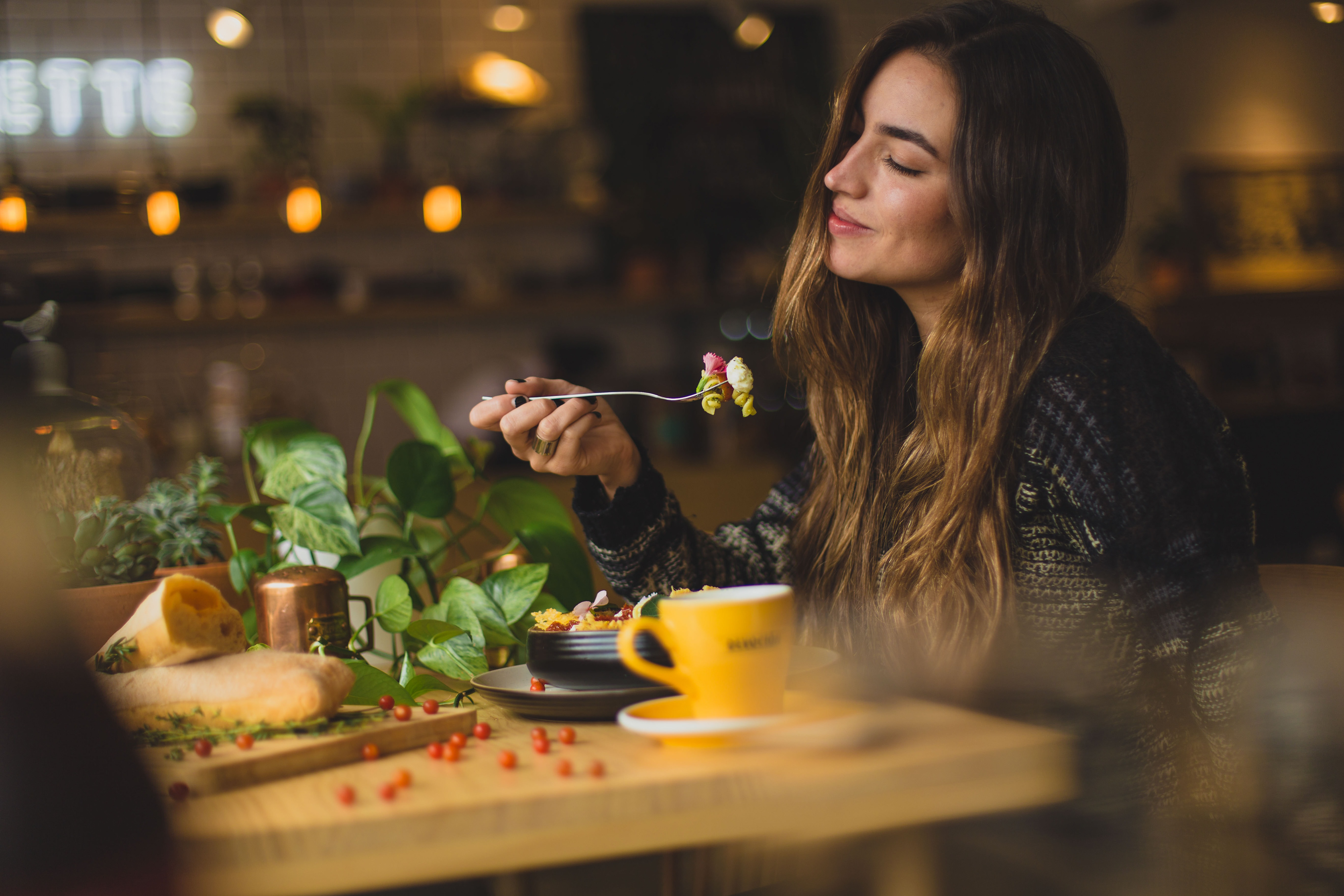 A young woman enjoys and eats her food with a smile on her face / The Gastro Label / www.gastro-label.com