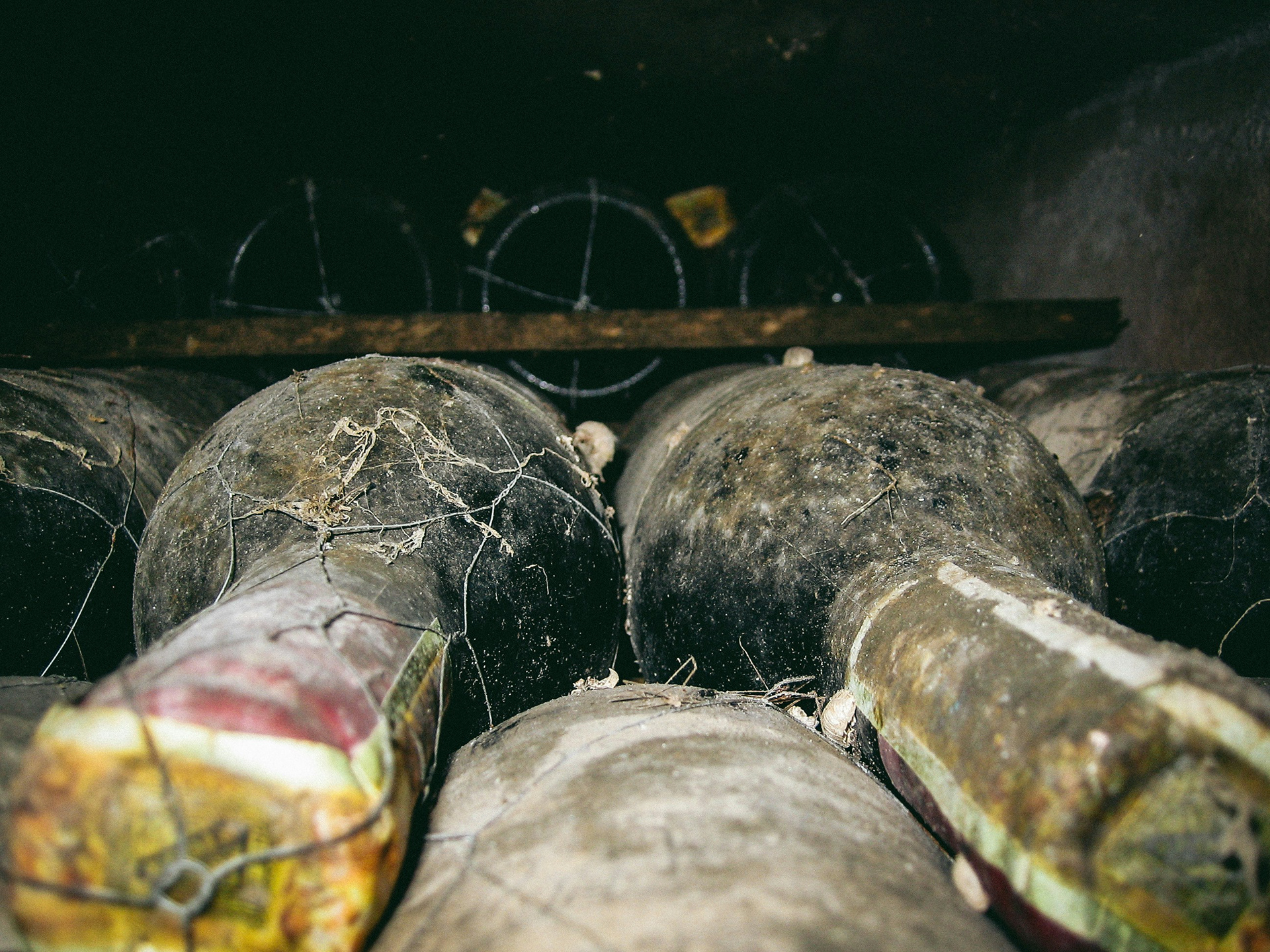 Two very dusty and very old bottles lying in a wine rack / The Gastro Label / www.gastro-label.com