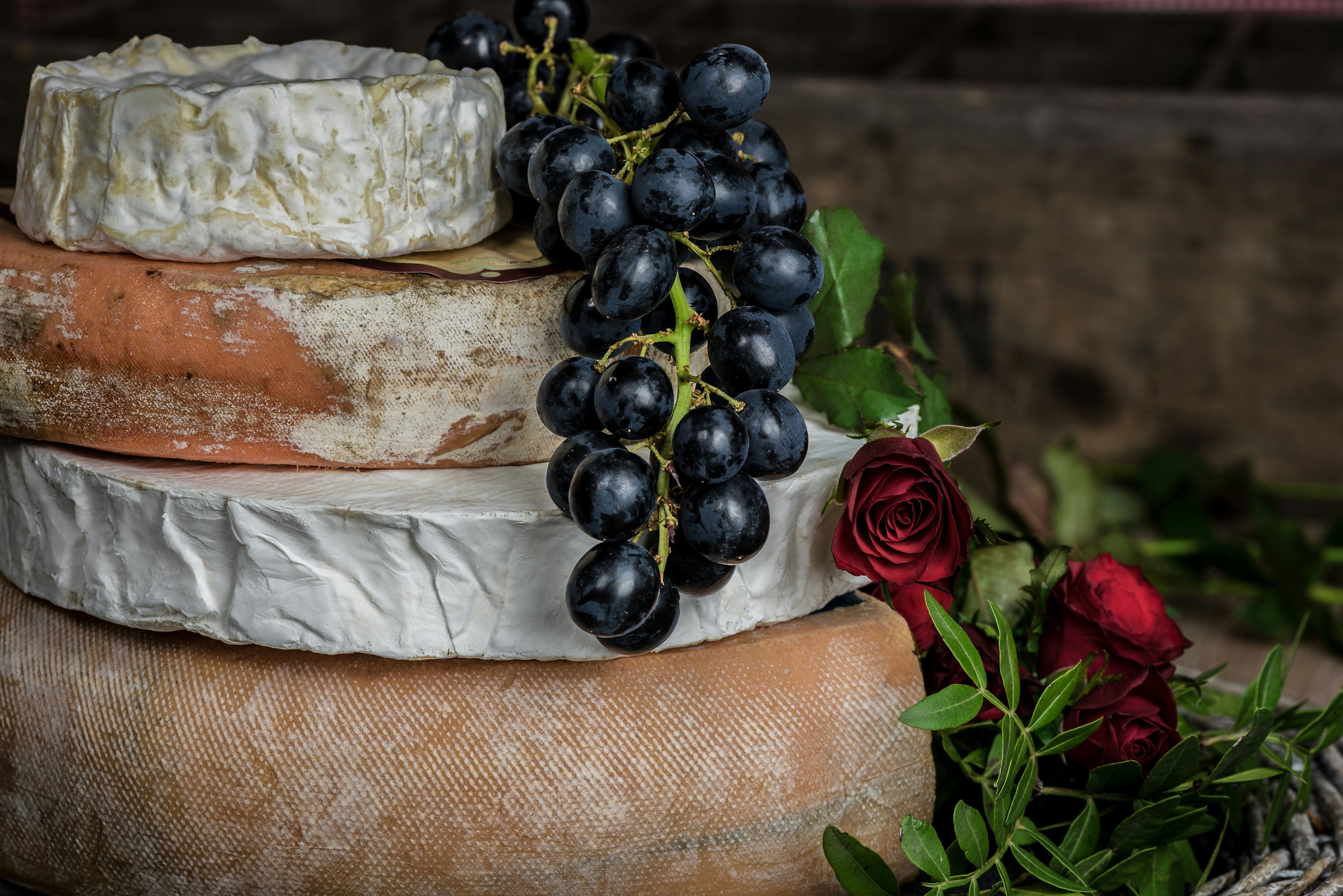 Various exclusive and old cheeses lined up and decorated with grapes and flowers / The Gastro Label / www.gastro-label.com