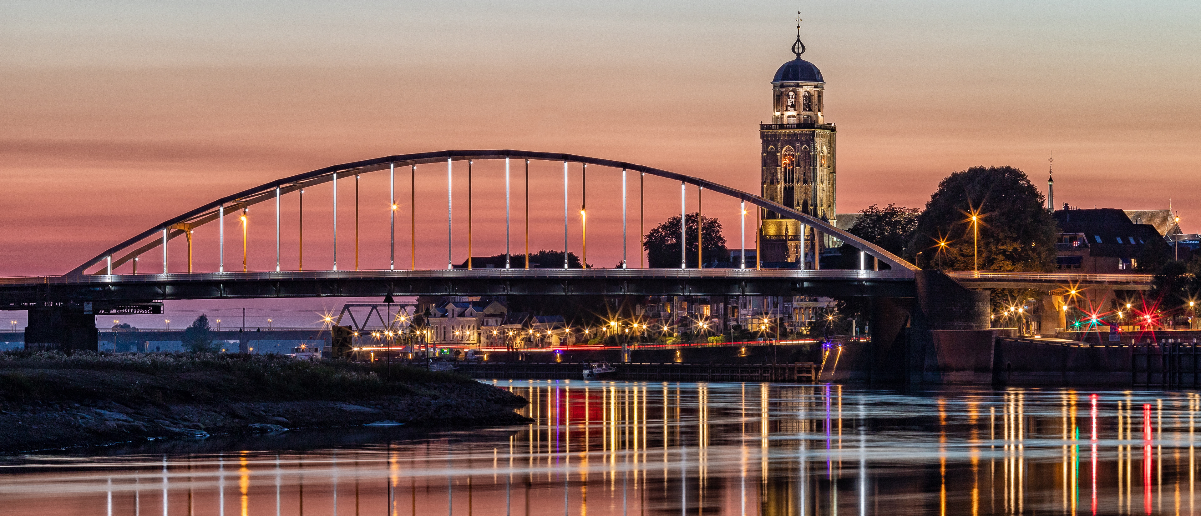 Deventer bij zonsondergang in de zomer met de Lebuinustoren en de Wilhelminabrug over de IJssel