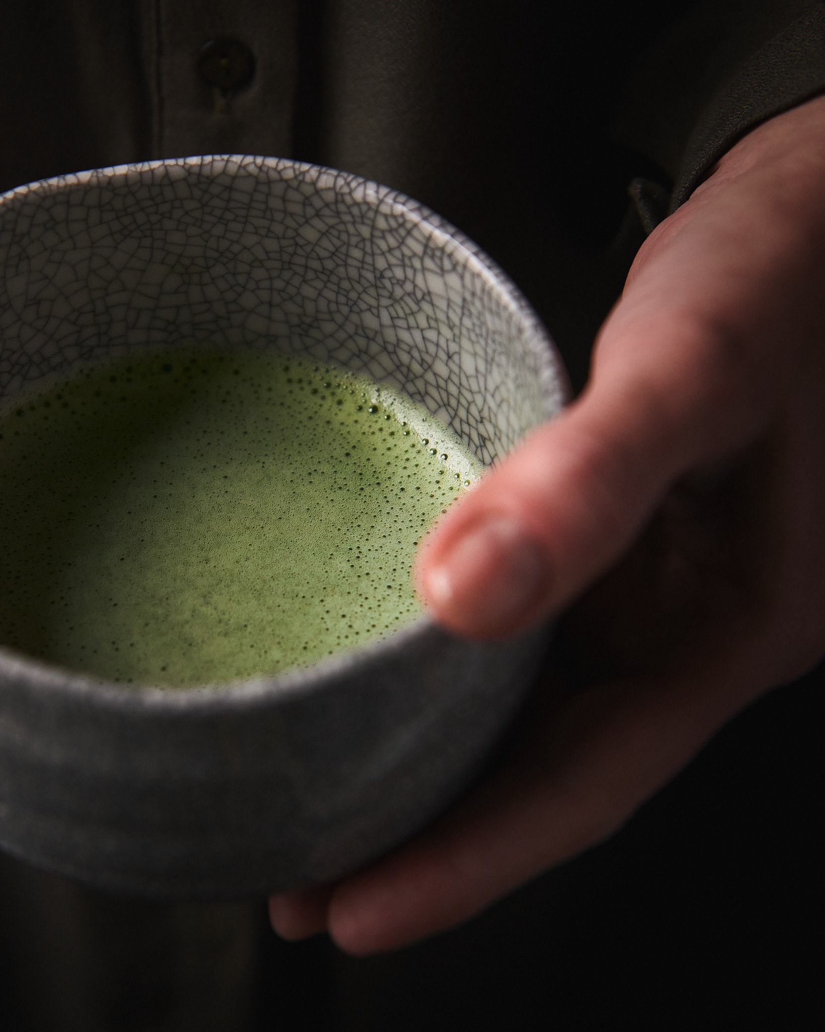 Kata Endrodi Montreal food and product photographer, lifestyle photography featuring a person holding a handmade matcha bowl with matcha wearing an oil green dress