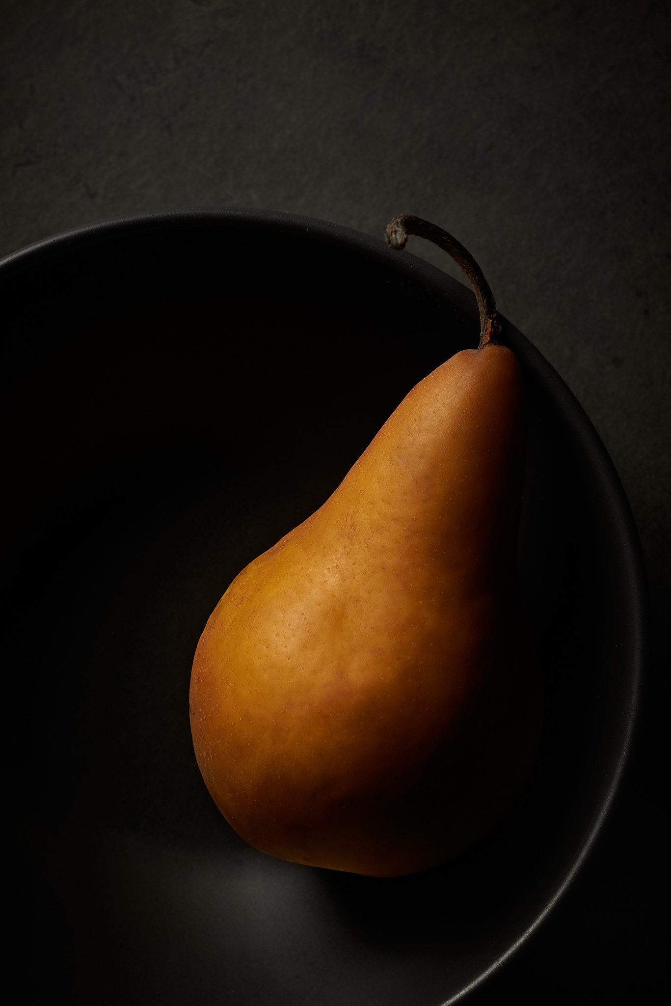 A food photography single pear image in black bowl, made by Kata Endrodi, a food photographer in Montreal