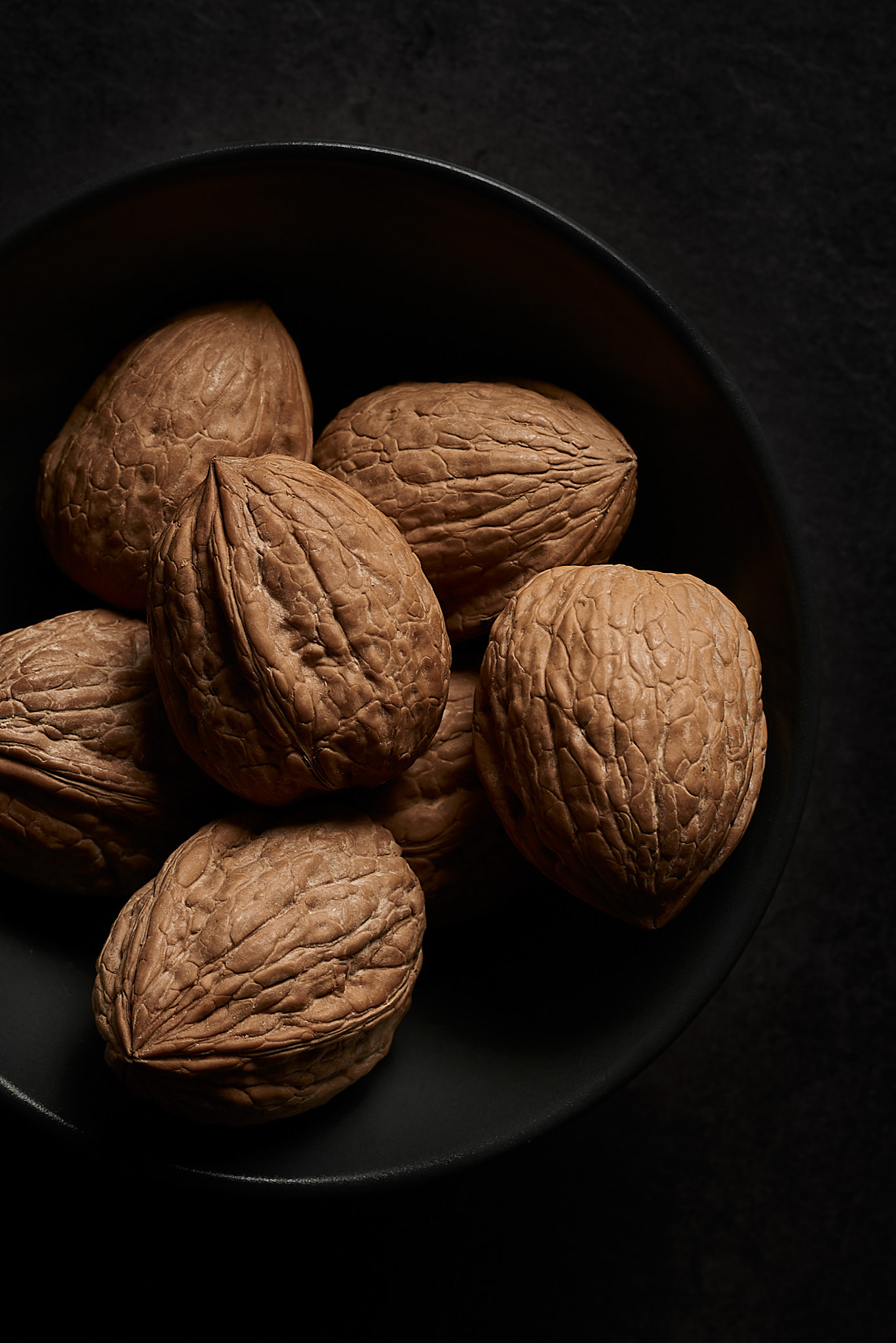 A food photography walnuts in shells image in black bowl, made by Kata Endrodi, a food photographer in Montreal