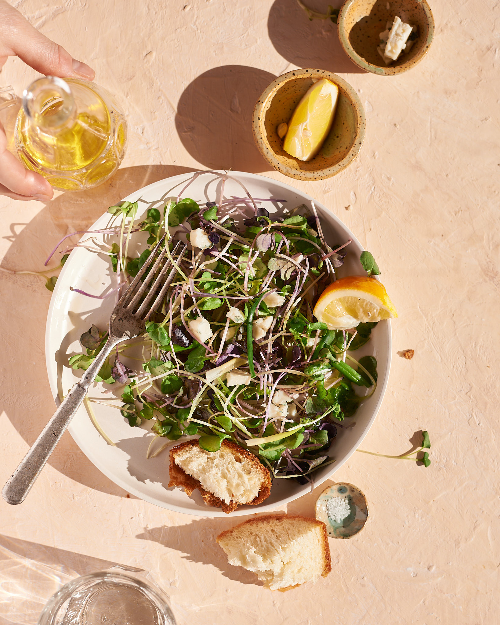 A food photography micro green salad image with olive oil, lemon, bread and blue cheese, made by Kata Endrodi, a food photographer in Montreal