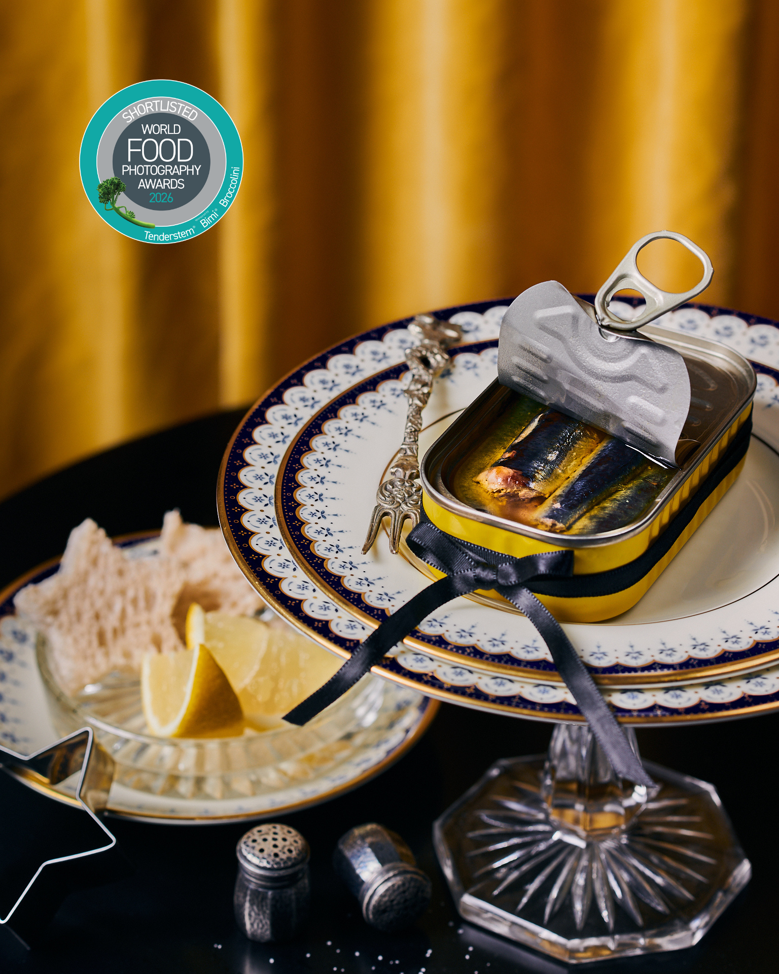 Kata Endrodi Montreal food and product photographer, yellow tin sardines on glass cake stand and vintage elegant plates with yellow velvet background 