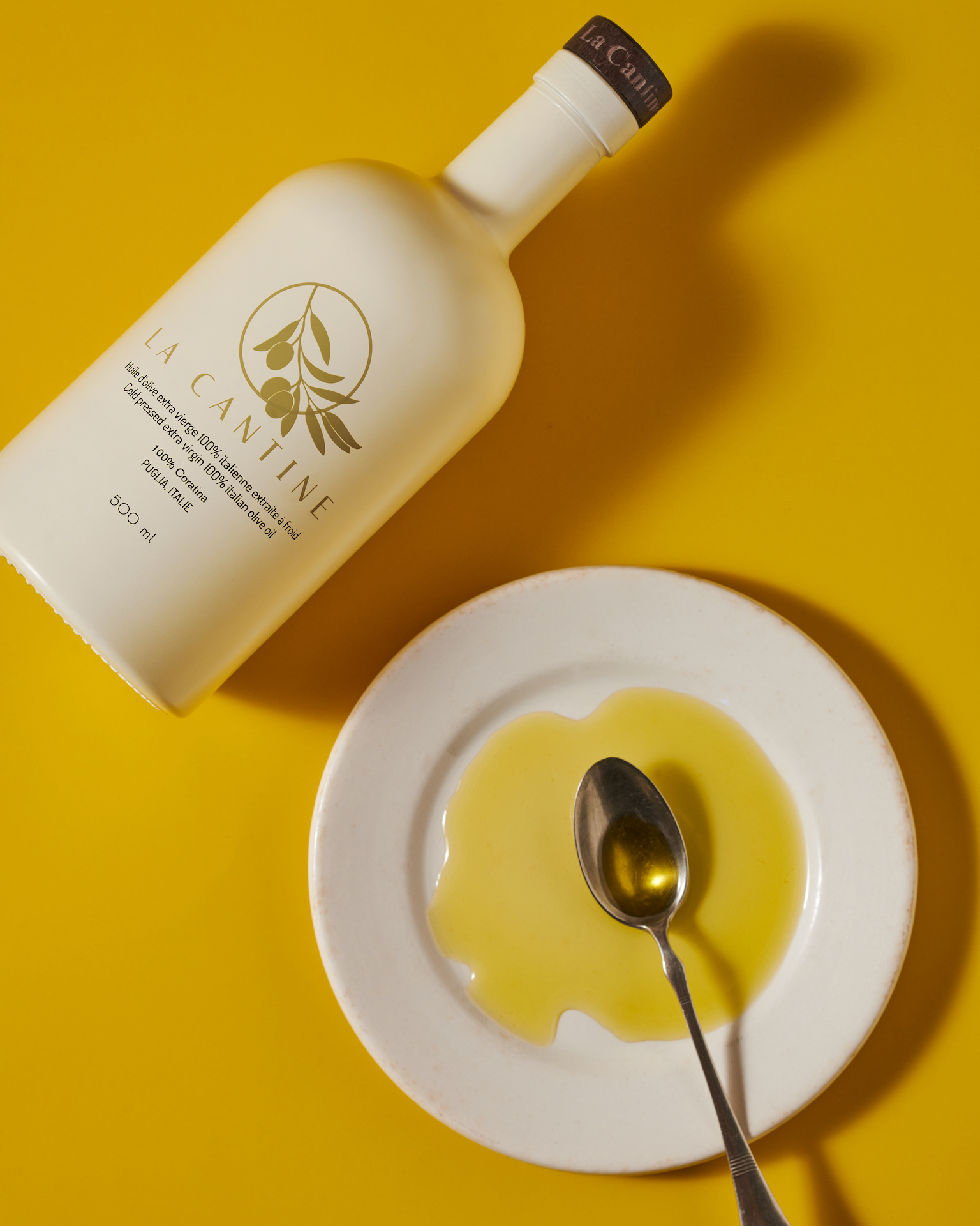 Kata Endrodi Montreal food and product photographer artisanal kitchen lifestyle photography featuring olive oil bottle and plate with oil and spoon on yellow background