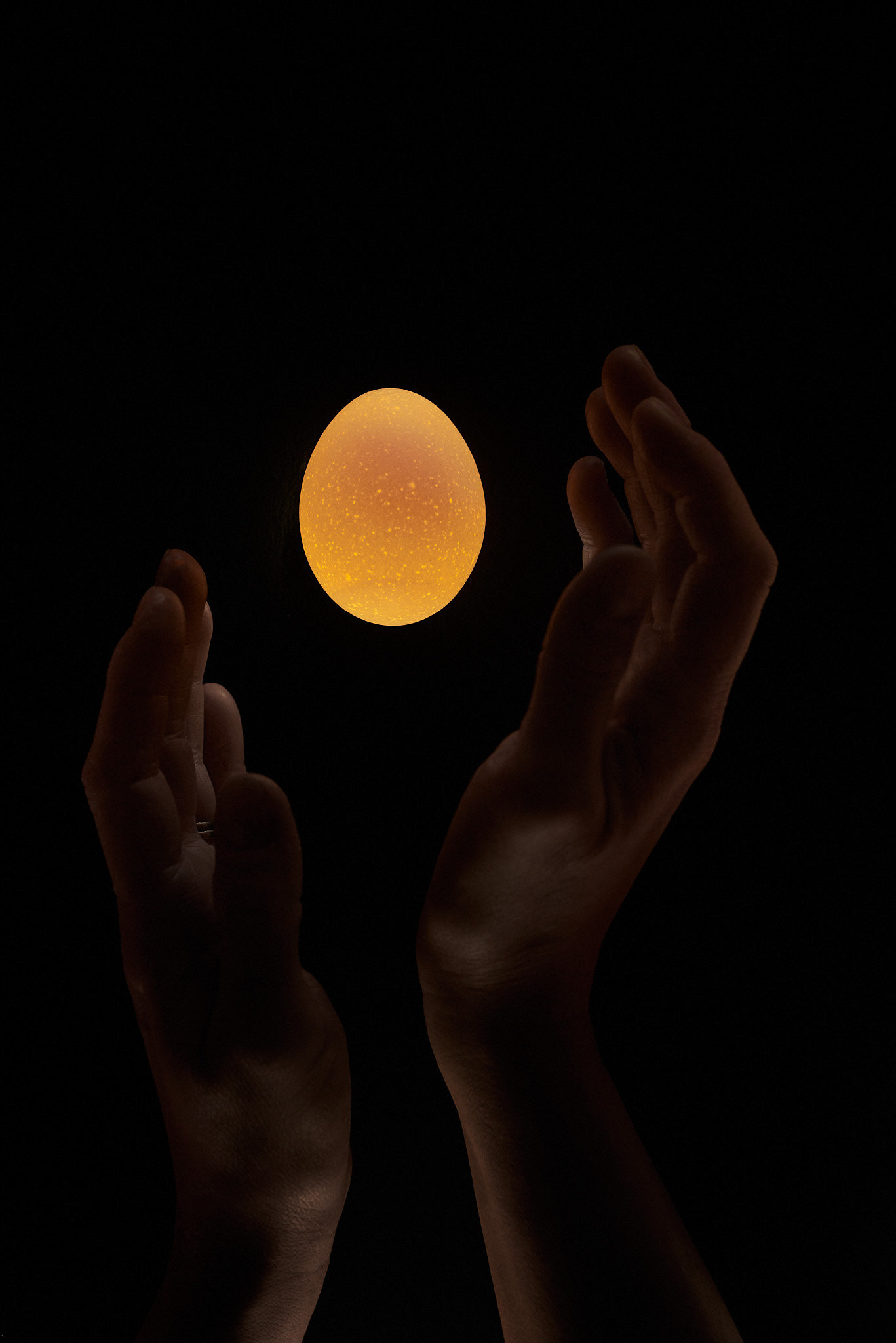 A food photography egg moon image with hands and dark backdrop, made by Kata Endrodi, a food photographer in Montreal