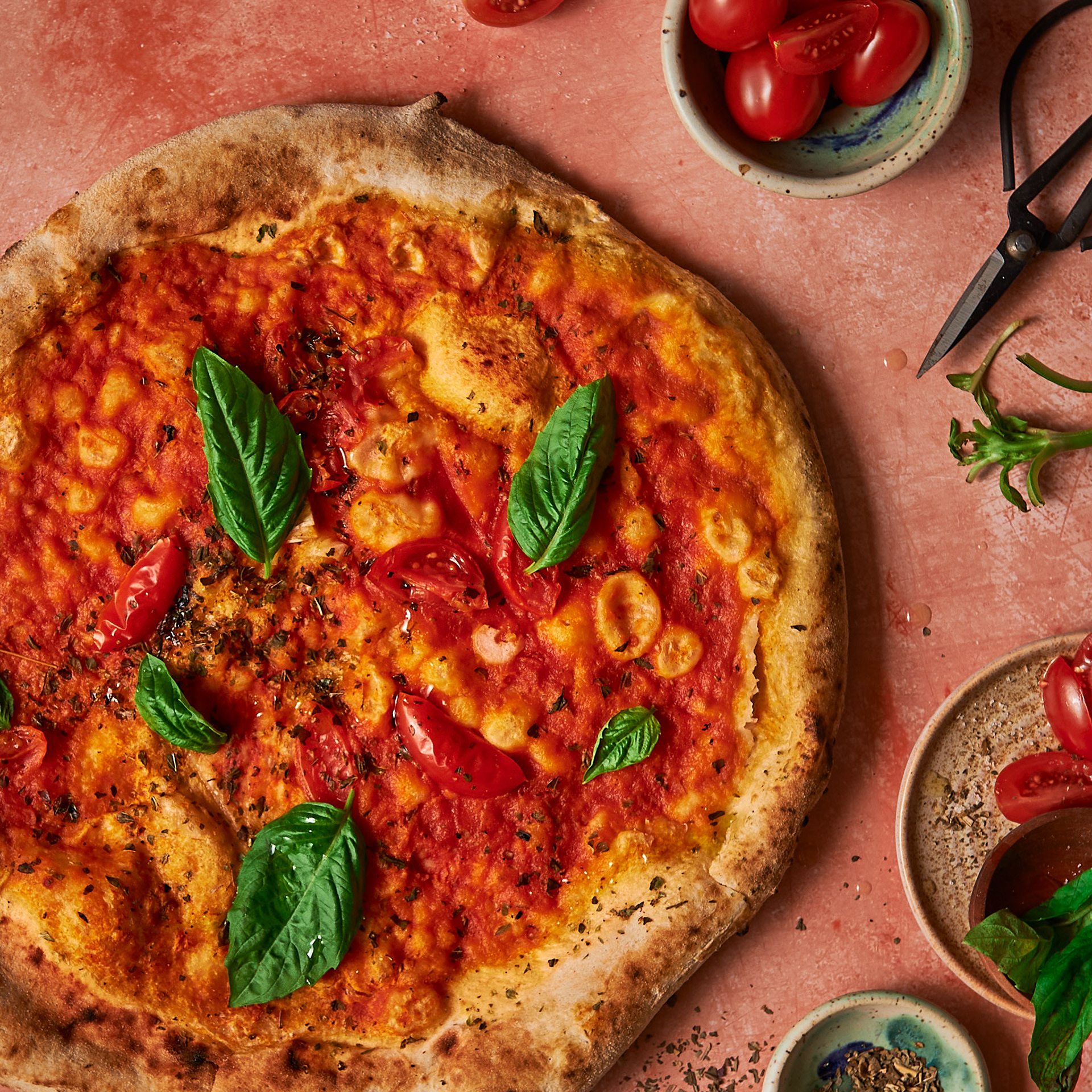 Kata Endrodi Montreal food and product photographer, artisanal baked pizza photography with fresh basil and tomatoes on a textured pink background
