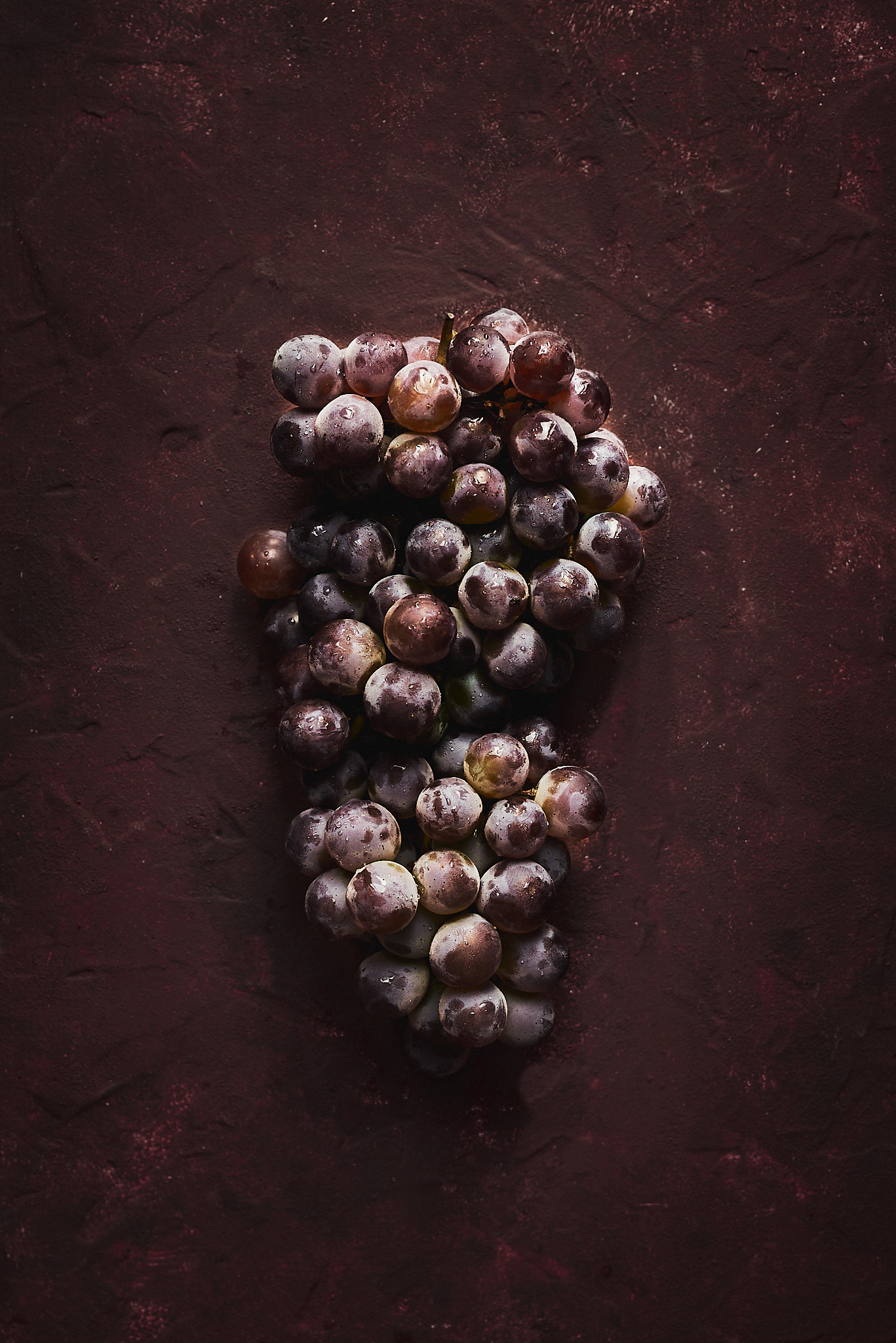A food photography bunch of red grapes image on dark red background, made by Kata Endrodi, a food photographer in Montreal