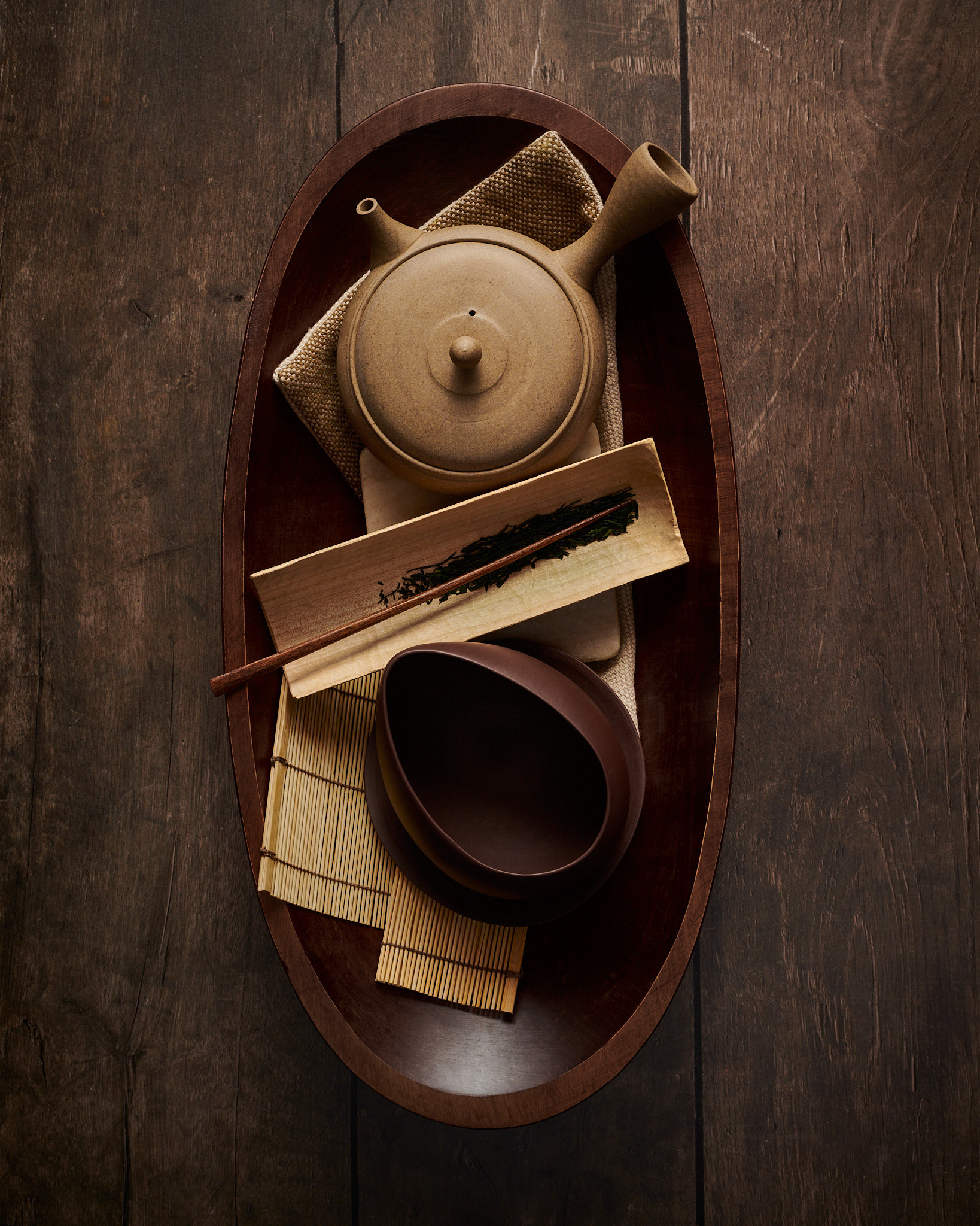 Kata Endrodi Montreal food and product photographer, lifestyle photography featuring wooden bowl with Japanese teapot and mug with saucer and loose leaf tea on weathered wood surface