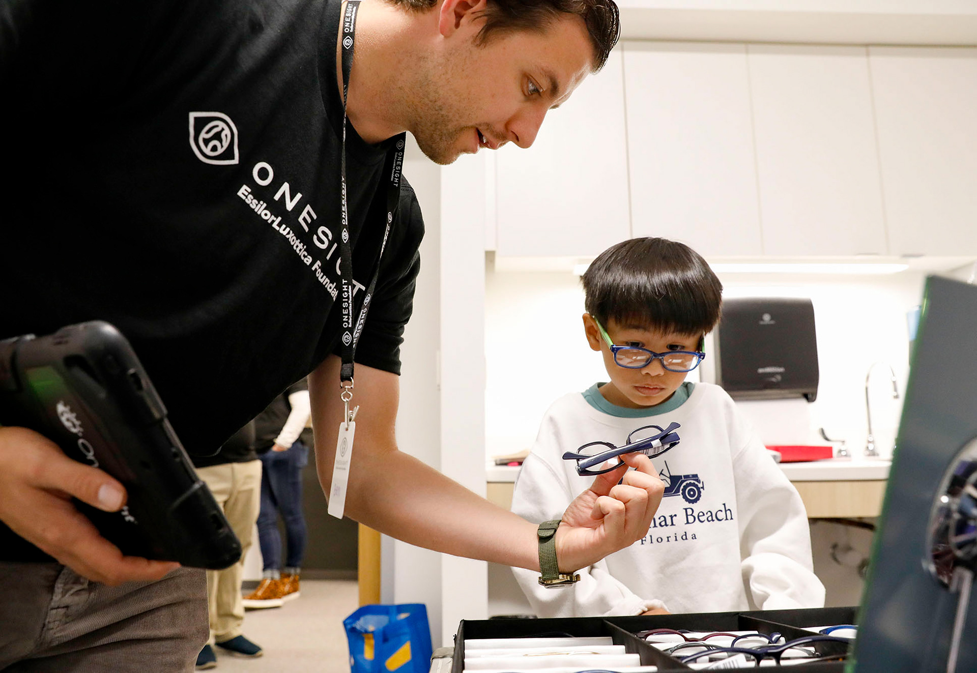 A OneSight Vision clinic volunteer helps first grader Derrick Nguyen find the right glasses frames for his first-ever pair on Monday, October 9, 2023. The OneSight clinic provided over 90 Lee’s Summit students of all grades with free eye exams and, if needed, free glasses.