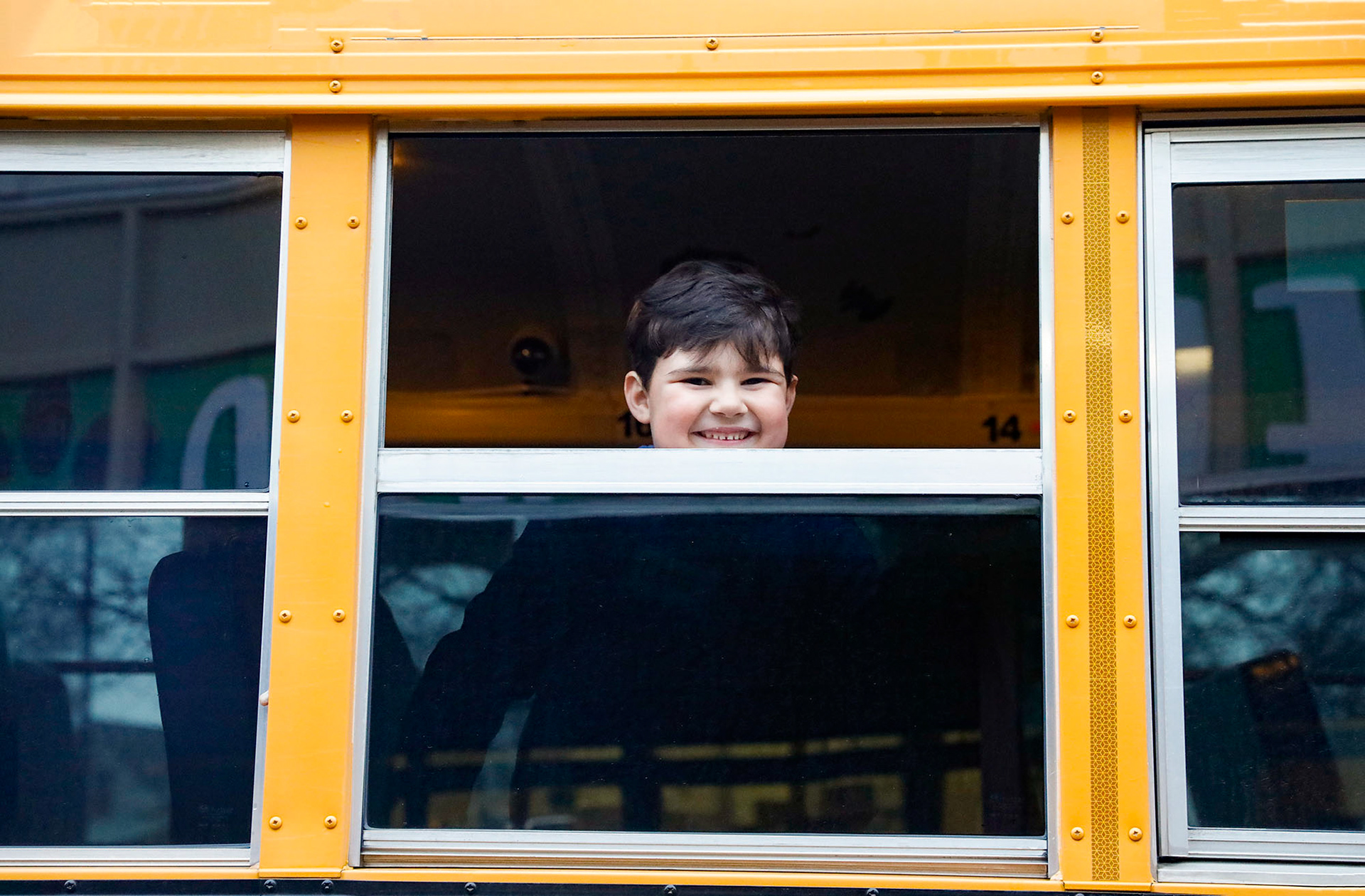 An incoming kindergartener smiles from an open bus window as he takes a tour of a school bus on March 7, 2024, to get comfortable before the next school year. 