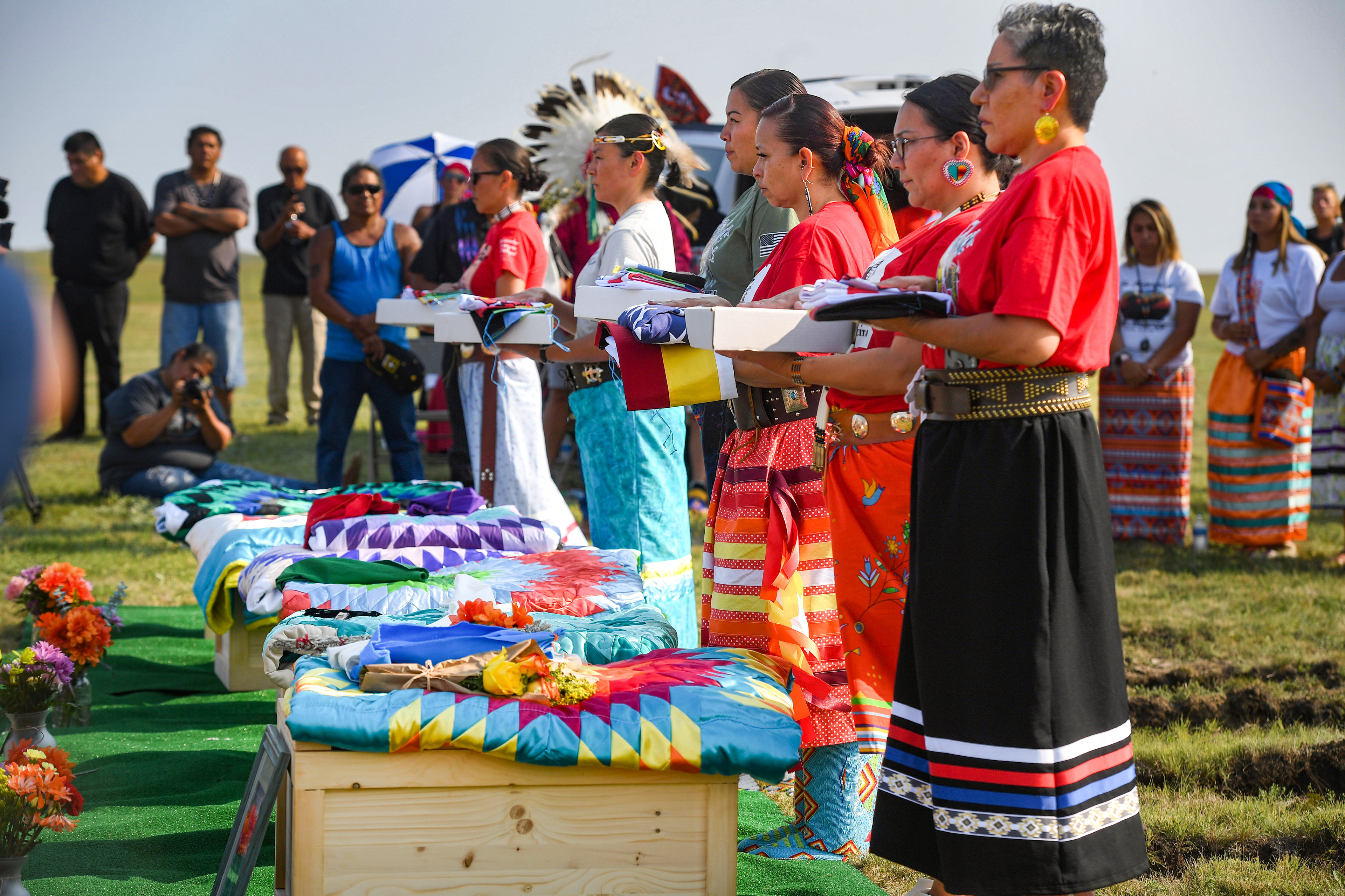 Members of the tribal color guard hold an American flag, a prayer flag and the Rosebud Sioux tribal flag for relatives of the Rosebud Sioux children returned home 142 years after their deaths on Friday, July 17, 2021 at the Rosebud Sioux Tribe Veterans Cemetery.