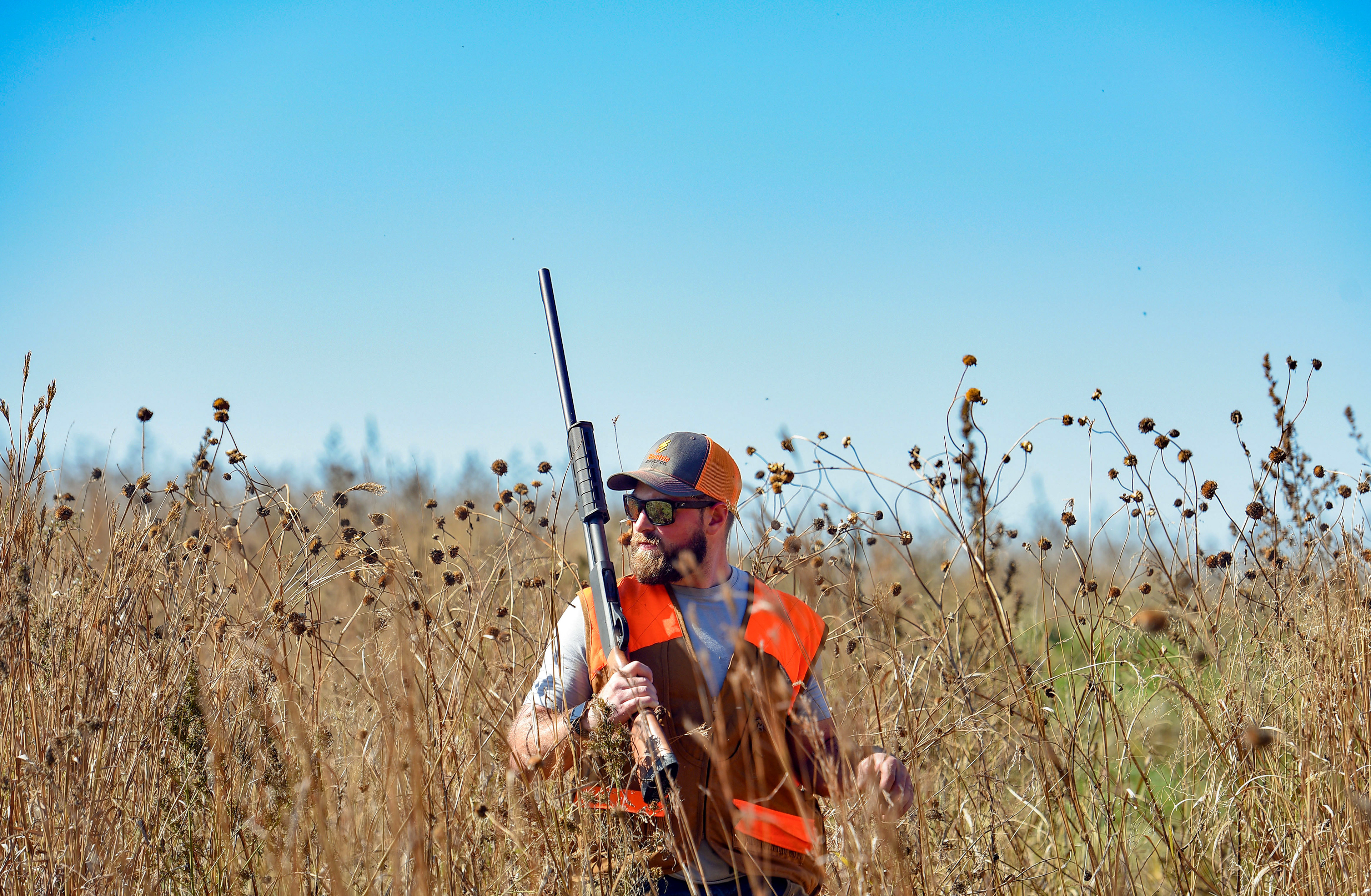 Bryce Lien keeps an eye out for roosters while wading through tall grasses during the pheasant season opener on Saturday, October 19, 2019, in Mitchell, SD.