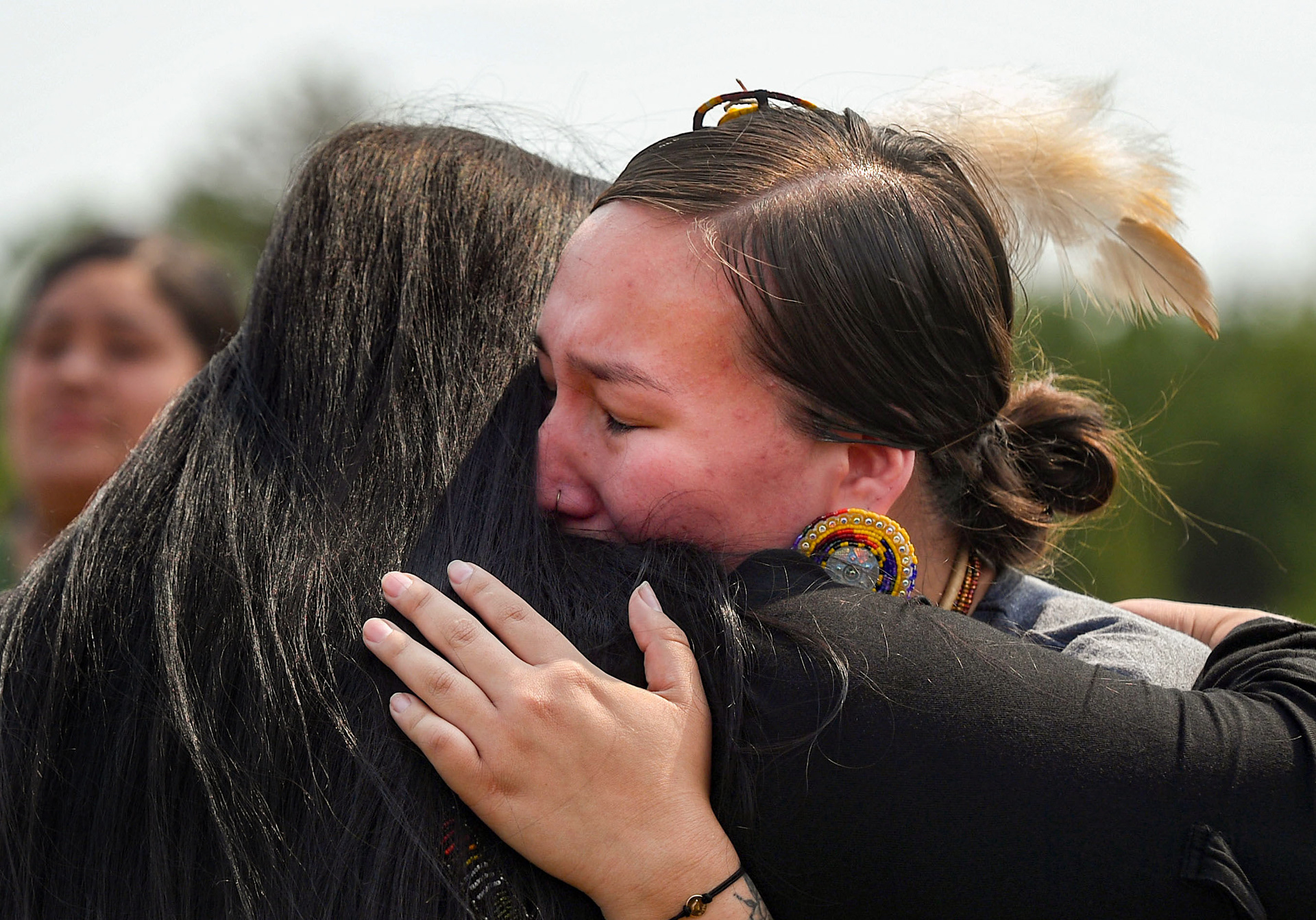 Women cry with each other as the remains of nine Rosebud children are returned home on Friday, July 16, 2021 at Whetstone Landing. 