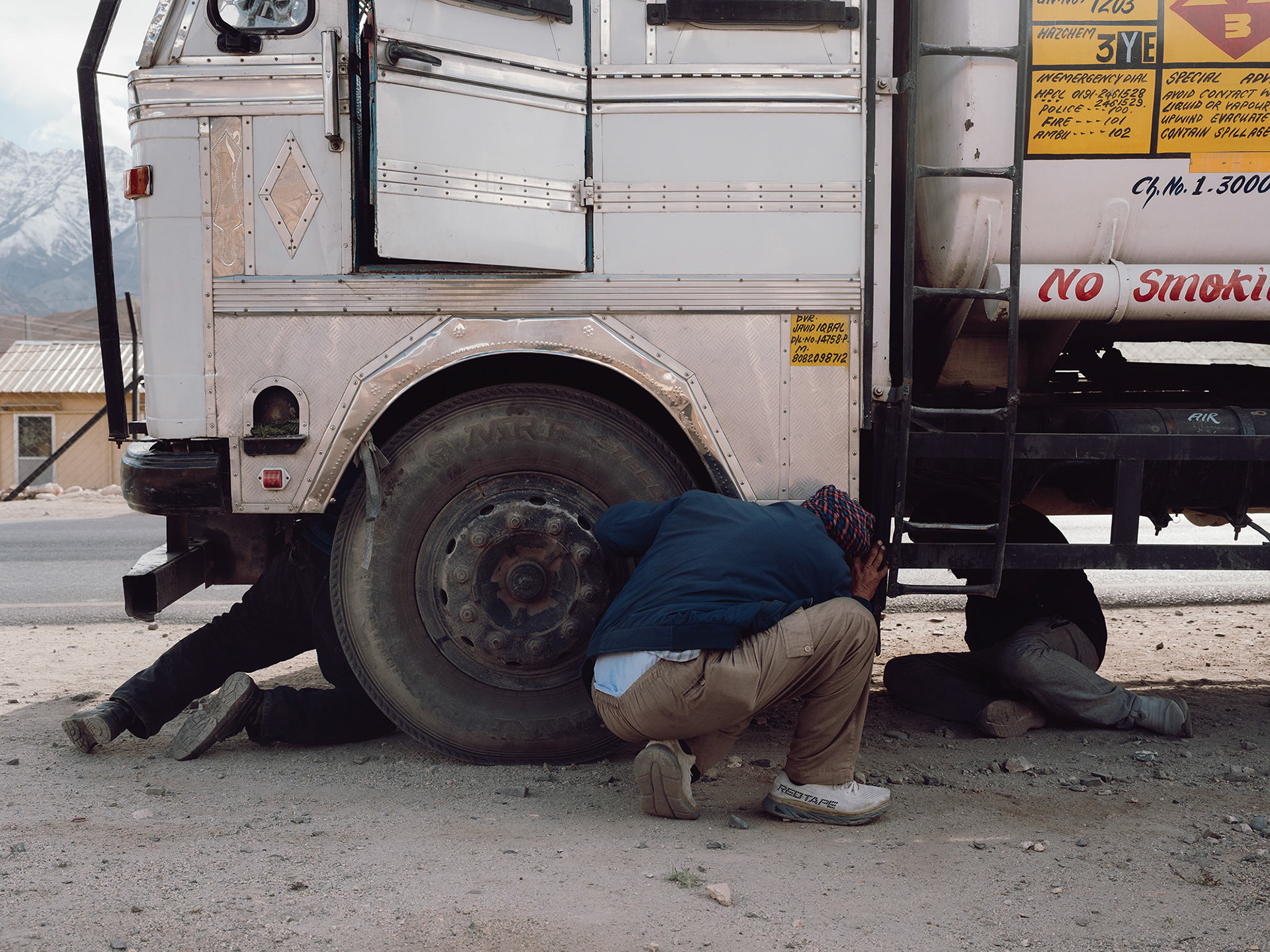 A truck carrying kerosene to an army base near Leh having engine problems in front of another army base along NH1. The two other drivers from the convoy are helping out.