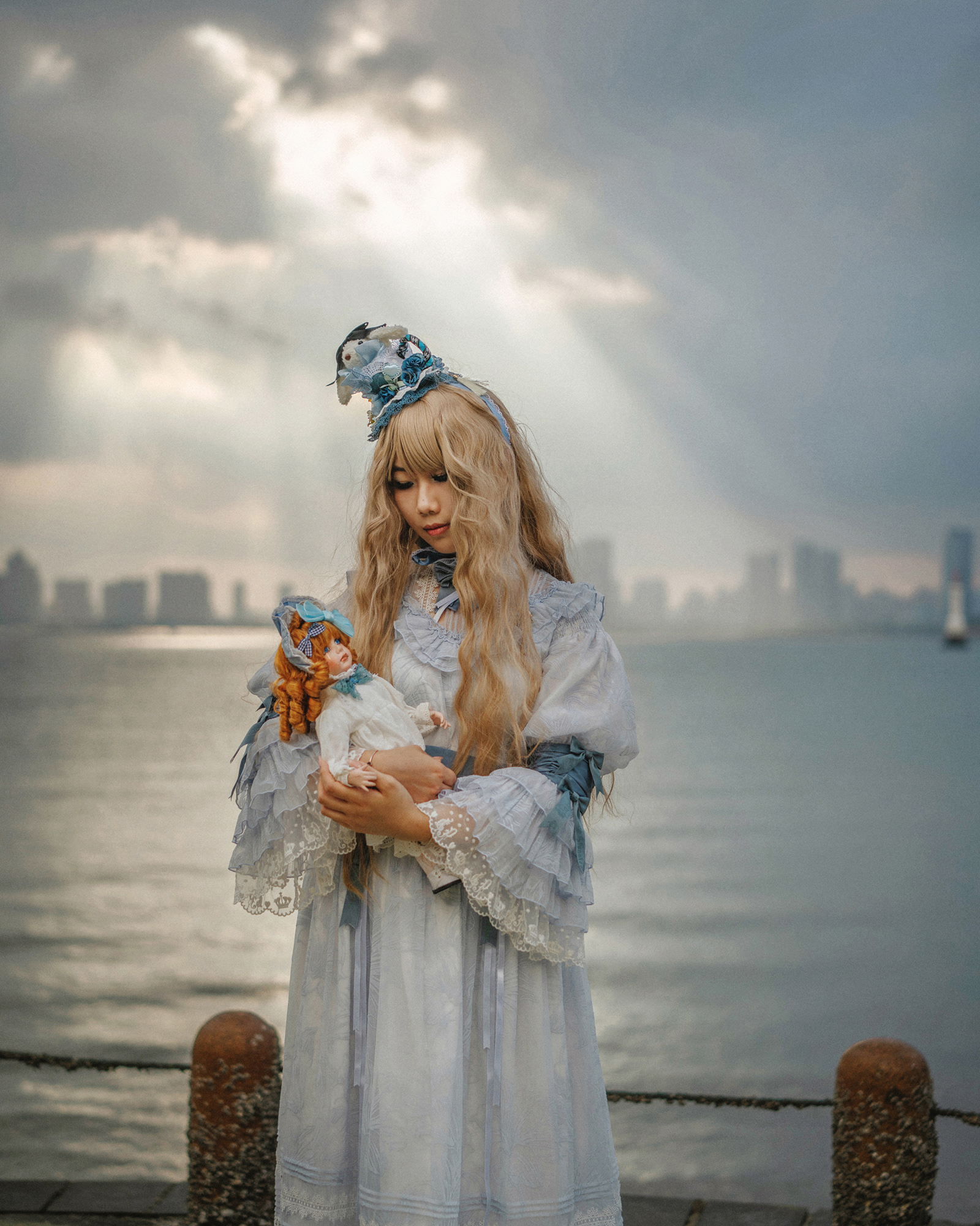 Tu Zi, 2024. Tu Zi is a third-year student at a university in Xiamen. She got into Lolita fashion because her first boyfriend was a “Brolita” (a male Lolita enthusiast). Nowadays, she frequently follows Lolita trends and has already bought 13 dresses this year. Lolita has sparked her love for all things cute and made her more attentive to the little details in life. She also enjoys crafting her own accessories to pair with her outfits. One evening, she brought out a doll she made herself and took a photo with it in the sunset.