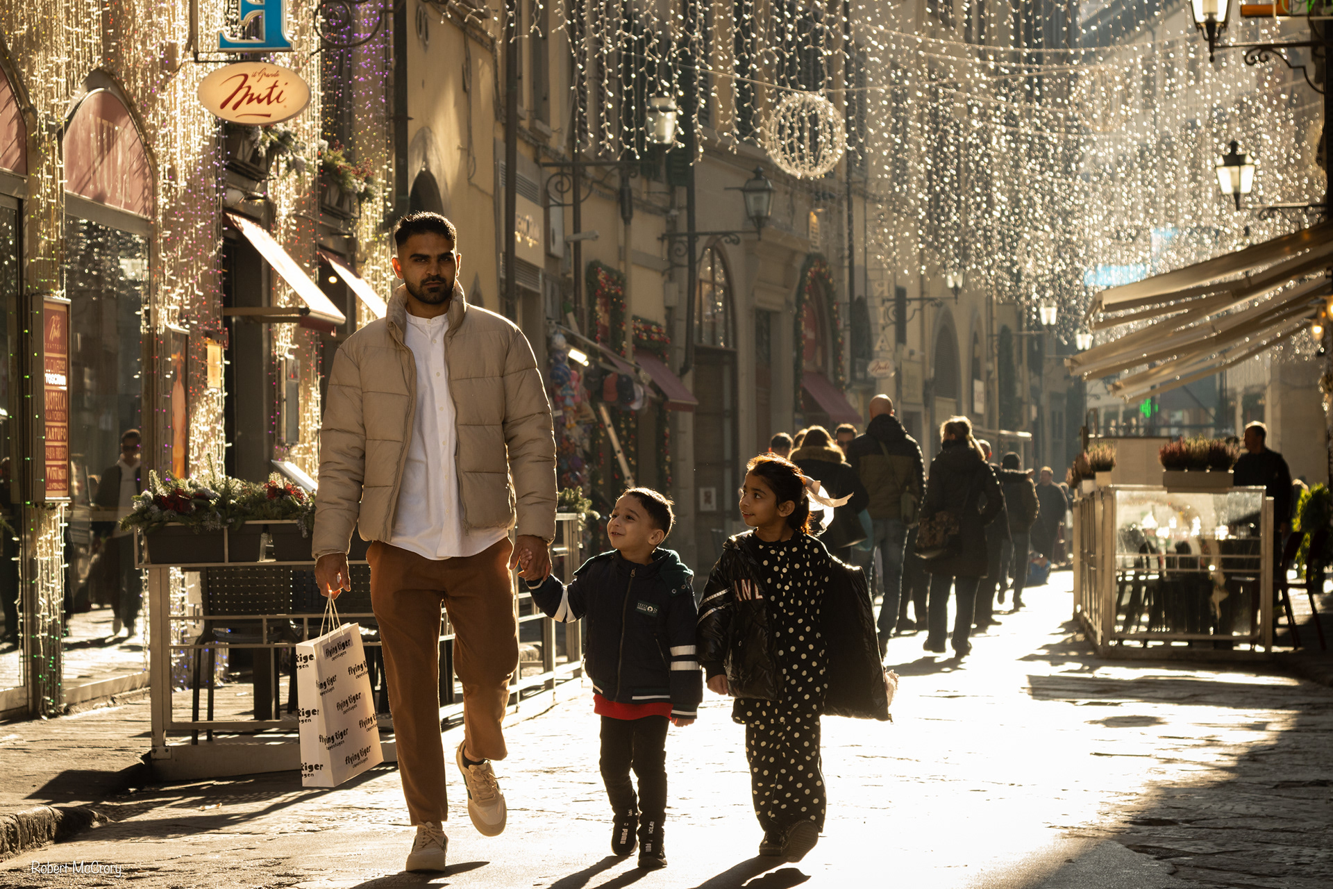 Street Photography, backlit family enjoying a walk in the cobbled Tuscan street