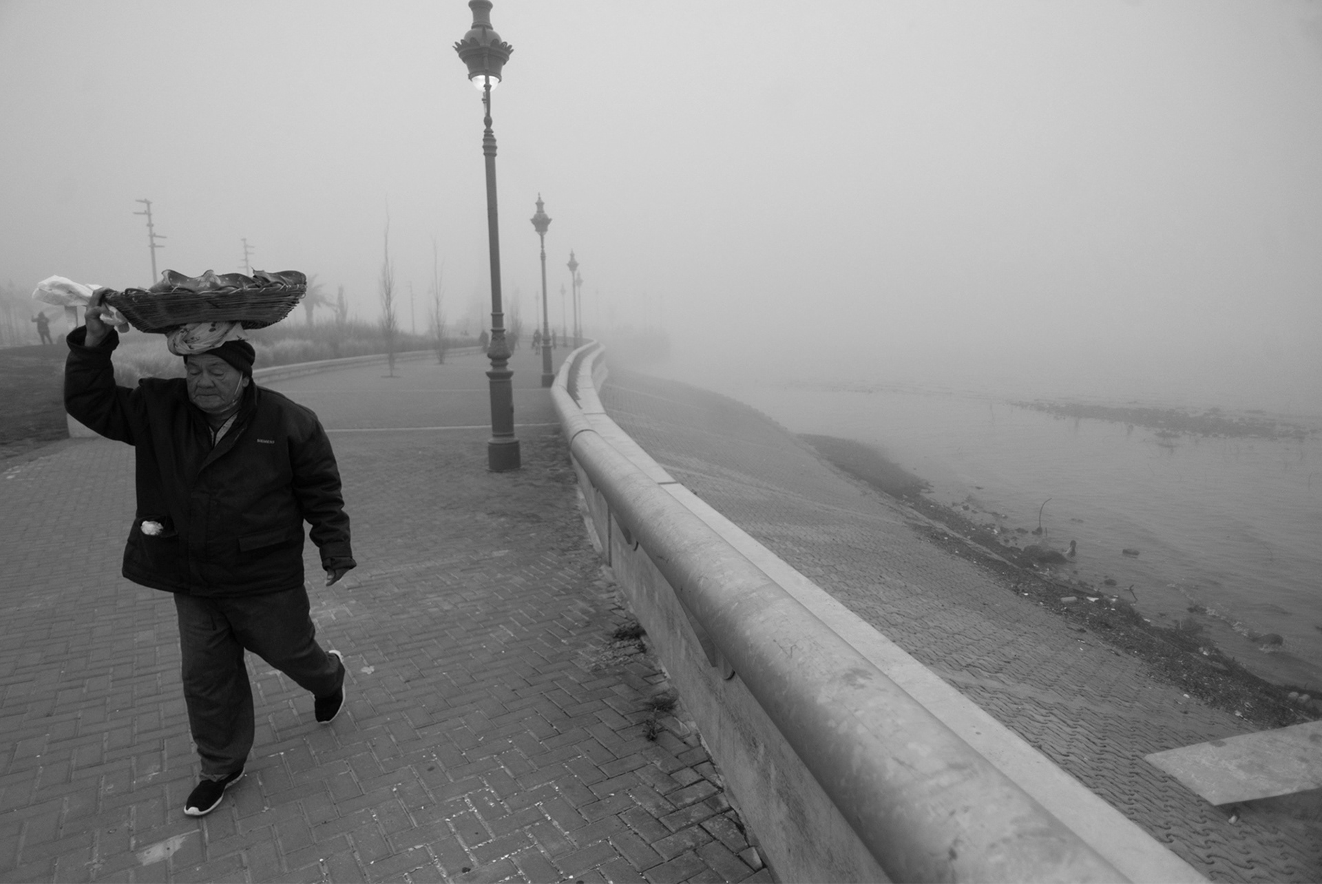 Panadero camina por la costanera de la Ciudad de Buenos Aires un día con neblina