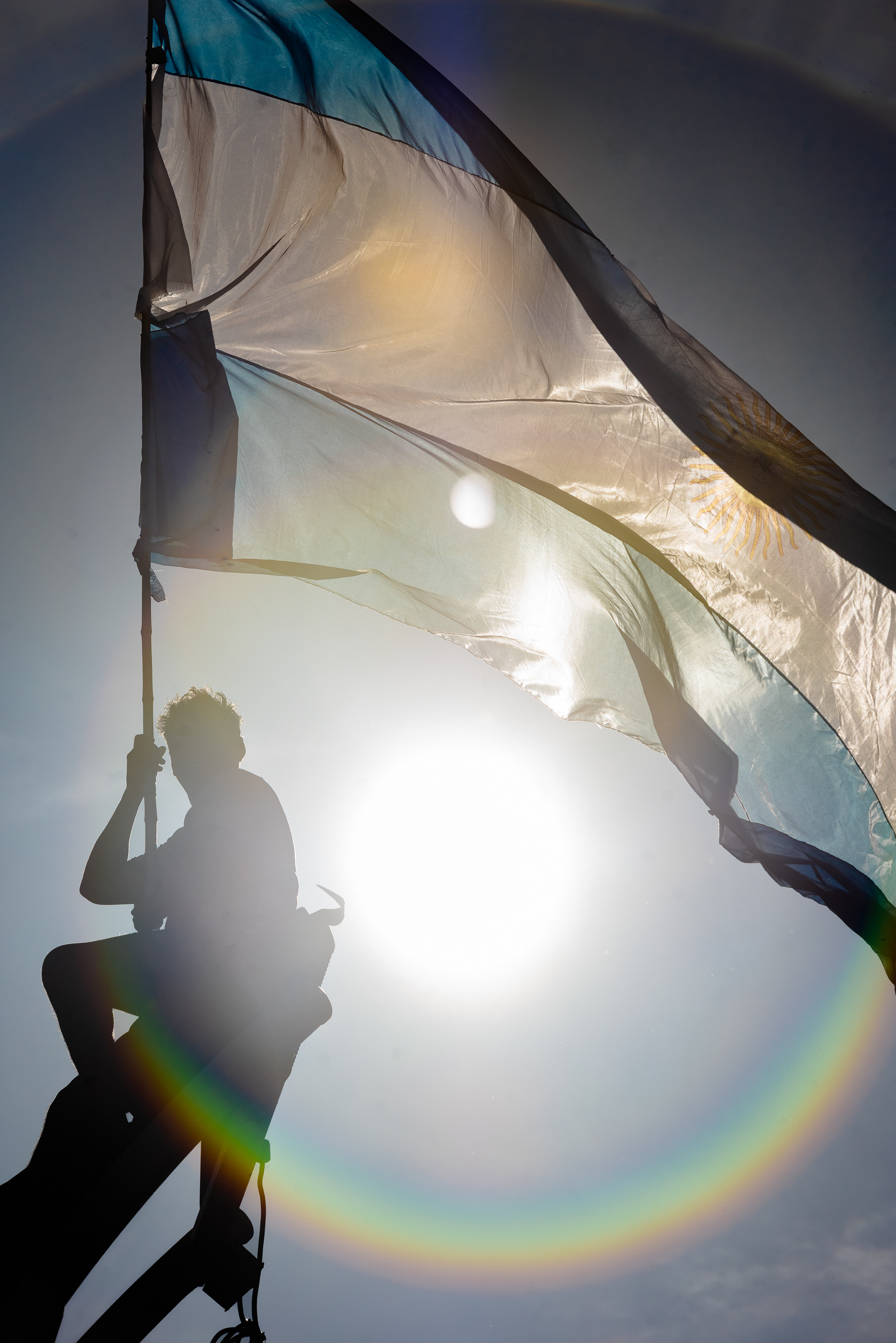 En la hora dorada de la conquista, un hincha es ungido por el sol, y al flamear la bandera, la convierte en un símbolo vibrante, el último destello del día que se hizo eterno.