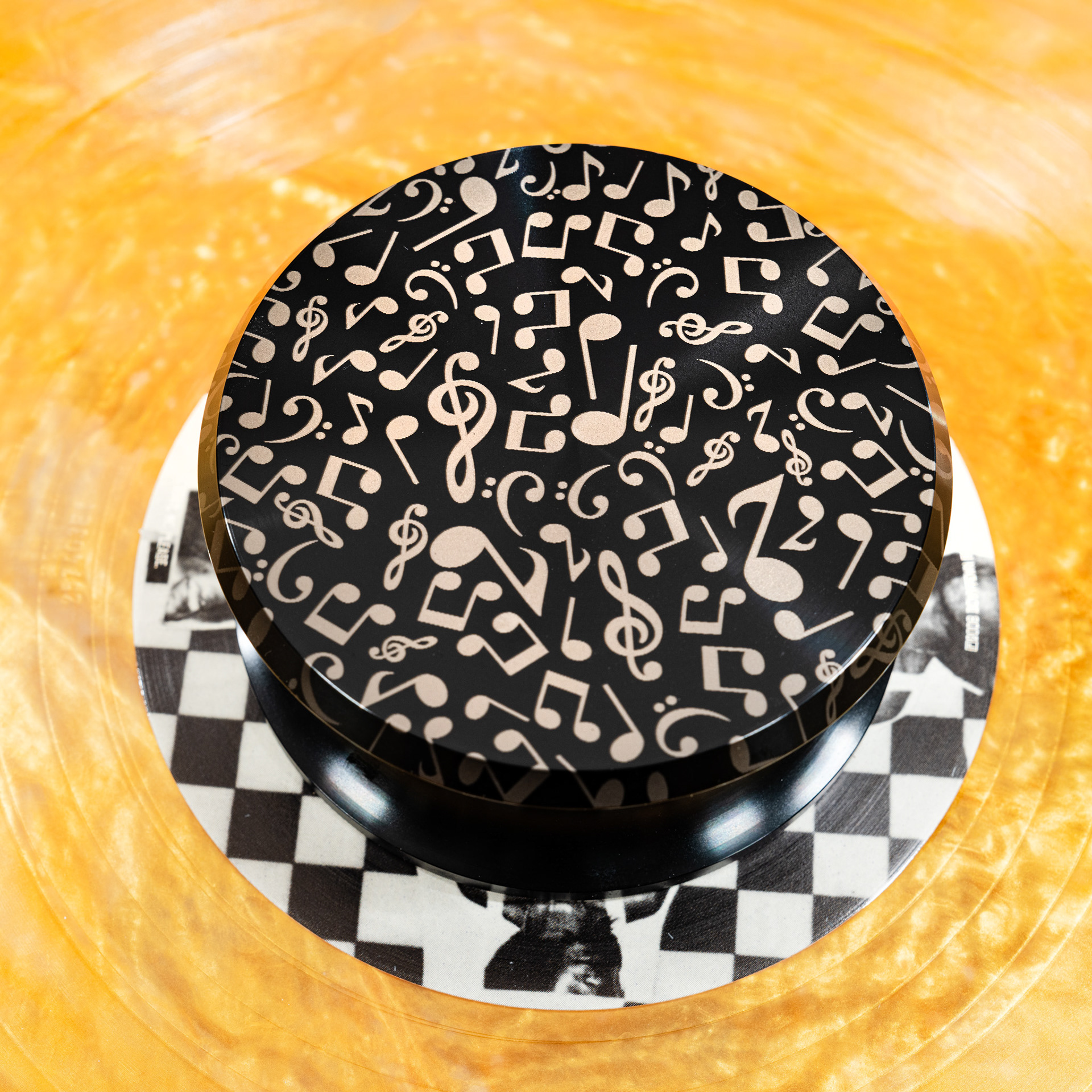 Scattered music notes engraved aluminum vinyl record weight stabilizer on a yellow vinyl record