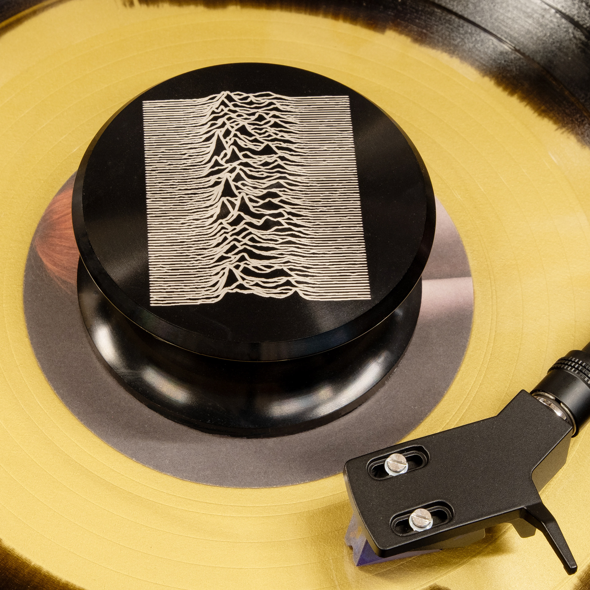 Waveform engraved aluminum vinyl record weight stabilizer on a yellow record and turntable