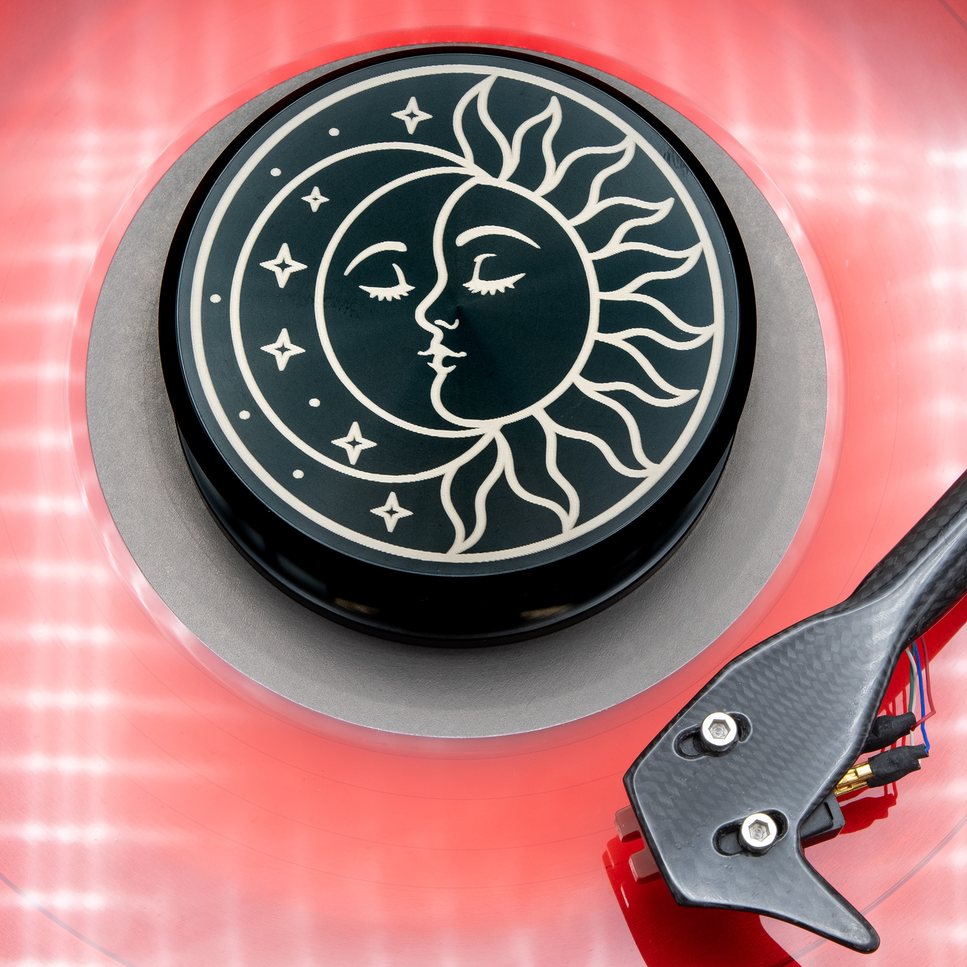 Sun and moon engraved aluminum vinyl record weight stabilizer on a red vinyl record
