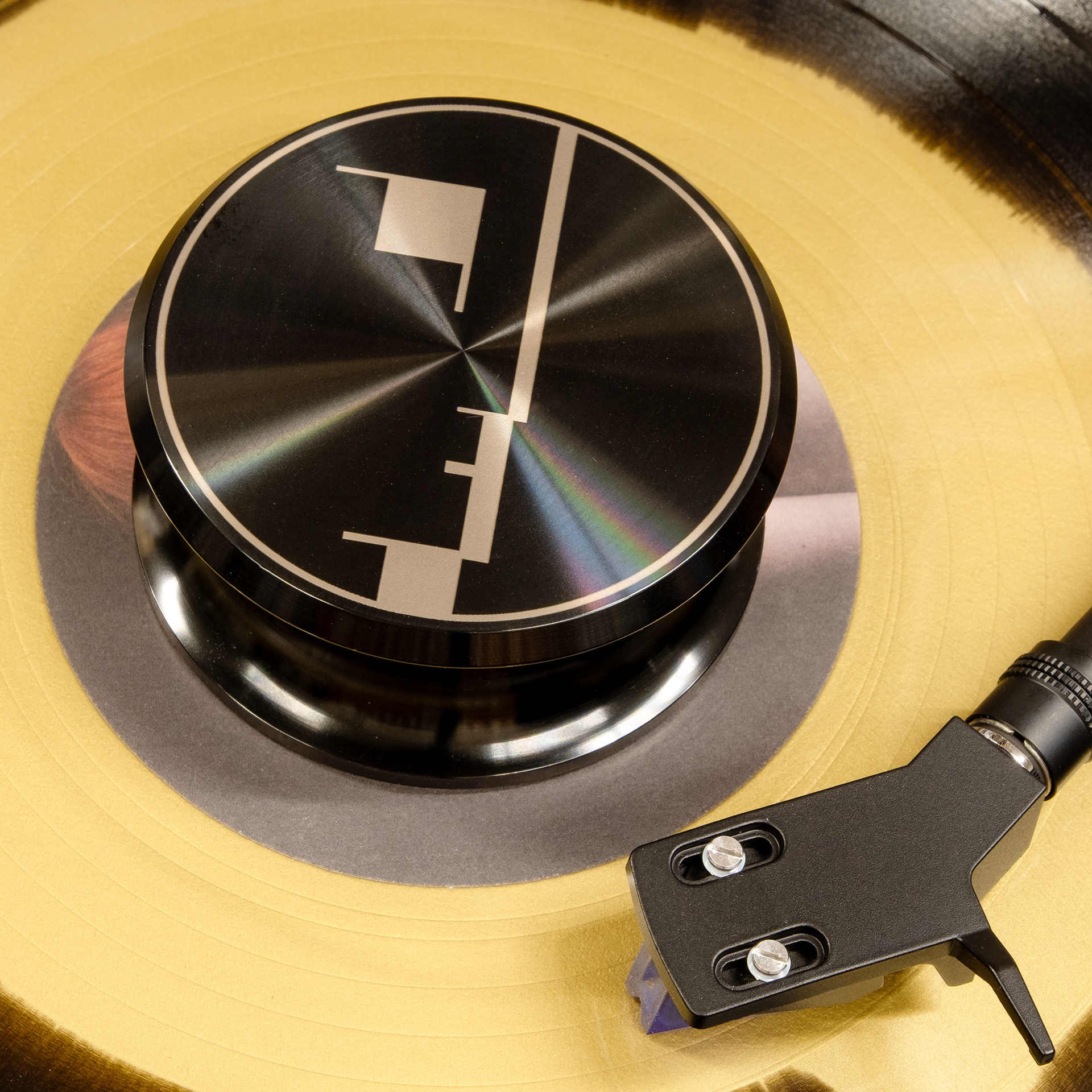 Geometric face engraved aluminum record weight stabilizer on a yellow vinyl record
