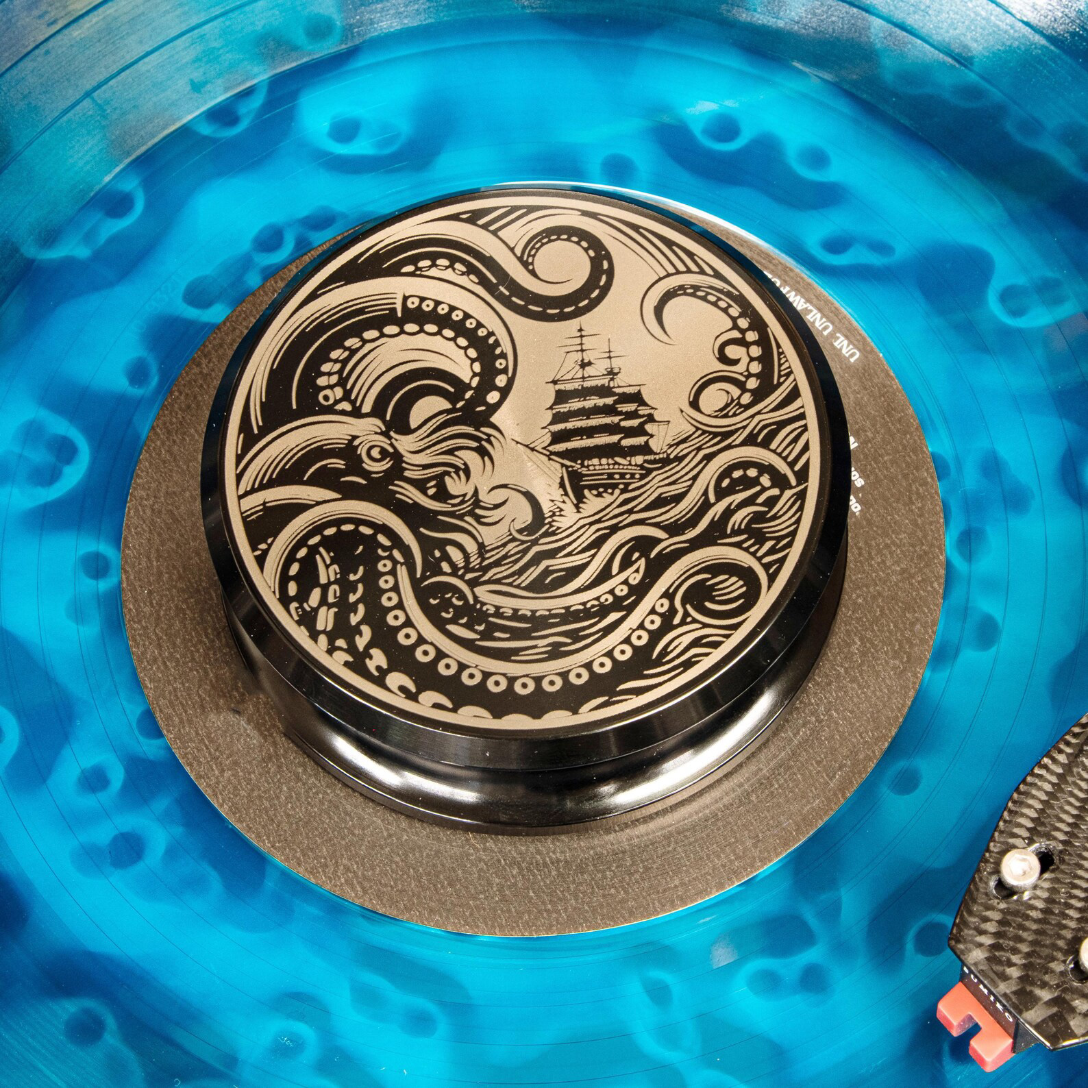 Kraken engraved aluminum vinyl record weight stabilizer on a blue vinyl record and turntable.