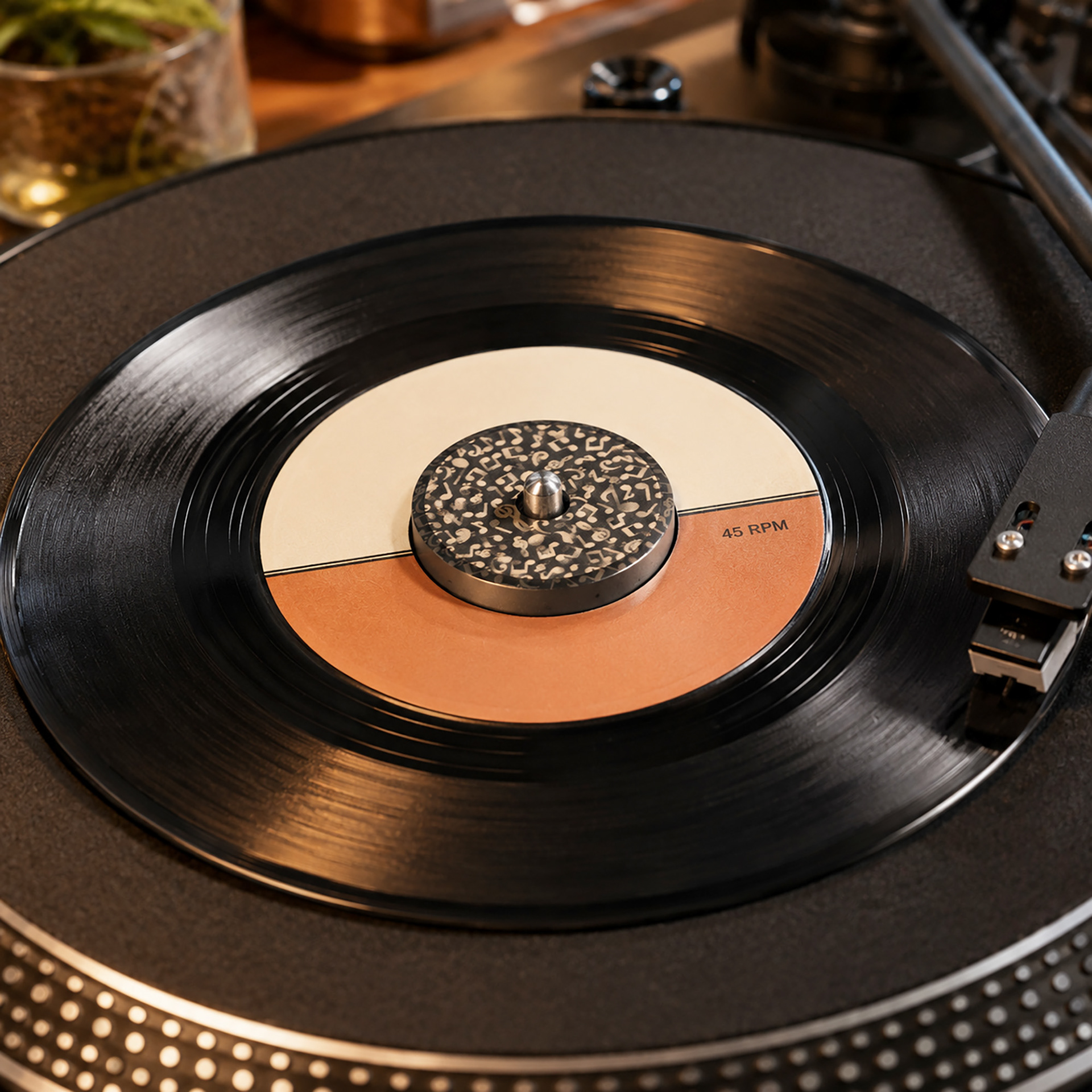 aluminum 45 RPM record adapter with emgraved musical notes design on turntable