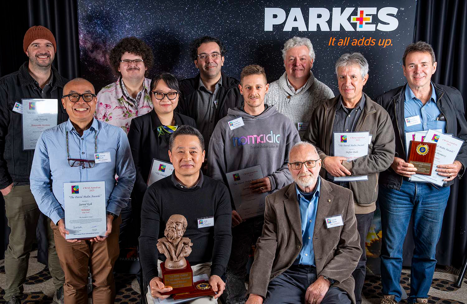 All the winning photographers L-R: Luke Tscharke, Jarrod Koh, Benjamin Alldridge, Lucy Yunxi Hu, Overall Winner Jong Lee (seated), Steeve Body, Jarrod Andrews, Niall MacNeill, Dr David Malin (seated), Stefan Buda, Kelvin Hennessy. Not shown Christian Gow, Guy Walpole, Troy Casswell  Not Present: Geoff Healey, Jacob Heppell, Anne-Maree McComb, Lachlan Wilson.