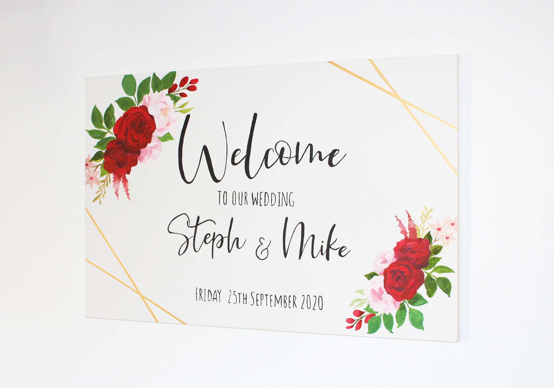 A2 Canvas framed in a thin light wooden border. Hand painted watercolour pink flowers with and eucalyptus green leaves in the top right and bottom left. In the middle are the words "Steph's hen do, Saturday 22nd August 2020" written in black
